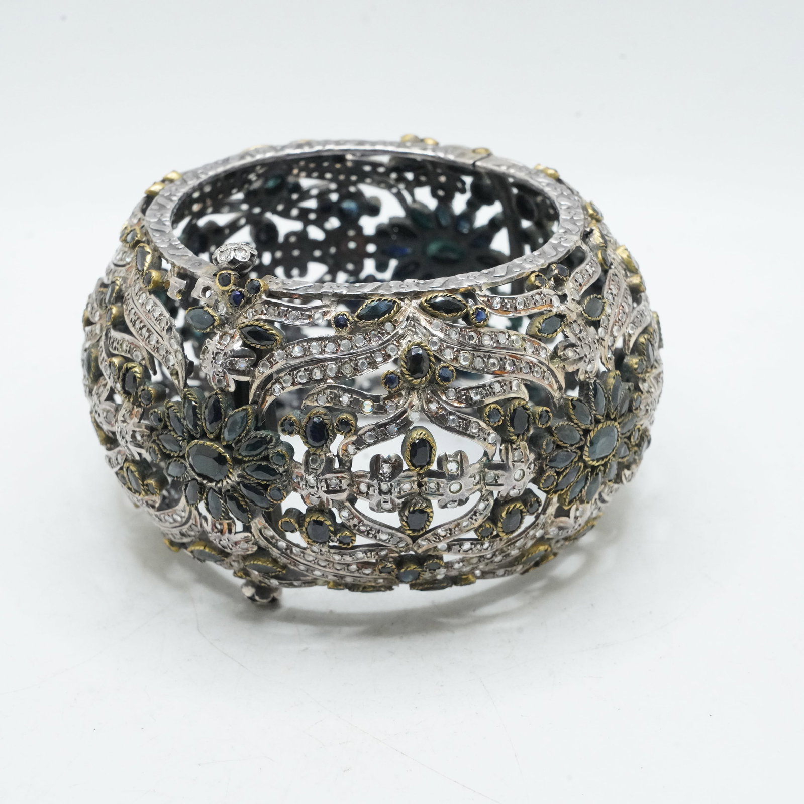 147.15 Grams Sterling Silver and Brass Wide Bangle Bracelet with Blue Sapphires, CZ. 2 in. wide,: 147.15 Grams Sterling Silver and Brass Wide Bangle Bracelet with Blue Sapphires, CZ. 2 in. wide, 2 1/2 in. opening.; Has 2 Pegs Closure. Note: missing stones