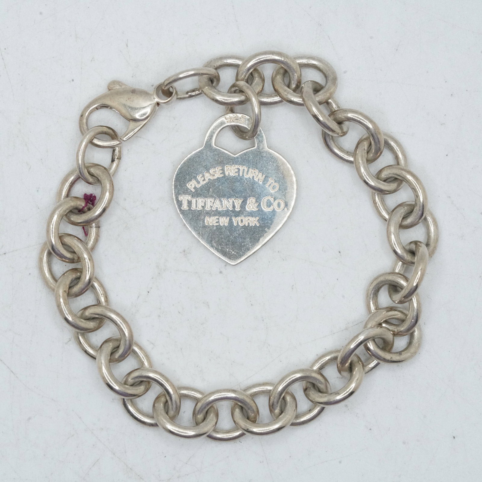 31.88 Grams .925 Sterling Silver TIFFANY & CO Charm Bracelet with Heart Charm, Fabric Pouch: 31.88 Grams .925 Sterling Silver TIFFANY & CO Charm Bracelet with Heart Charm, Fabric Pouch. "Please Return To Tiffany & Co New York", Size heart charm 7/8 in. x 1 in.; bracelet 7 1/4 in. x 1/4 in.