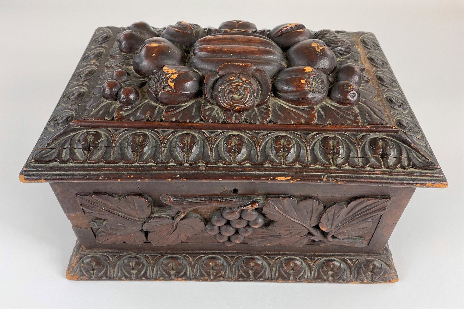 A Carved English Powder Box in Mahogany: Carved with a cornucopia on the lid and a berry and vine relief to the front and side panels. Height: 9.5", width: 15", depth: 10.5"