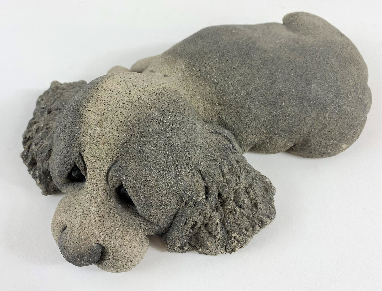 Lou Rankin (1929-2016) Puppy Concrete Sculpture: Concrete, with glass eyes. A recumbant spaniel, signed and numbered 82/250 to the underside, dated 1989; lg. 10.5". Lou Rankin was originally a cartoonist working in California, but over time he devel