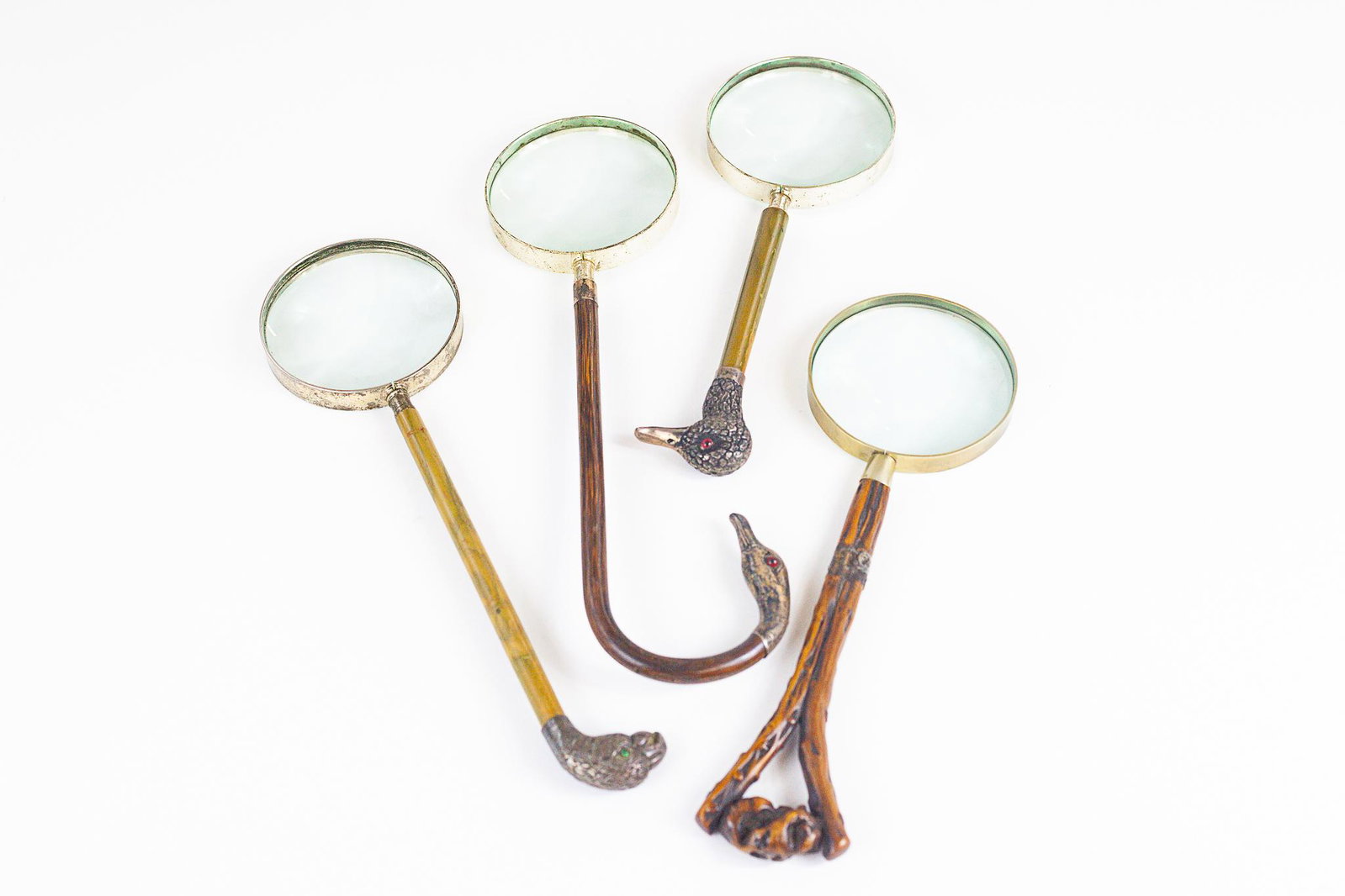 Fine Collection of Magnifying Glasses with Ornamental: A group of four magnifying glasses, each with bone handles, one with bamboo handle, with one having a hallmarked sterling duck handle, another goose, and also an eagle; lg. 14.5".