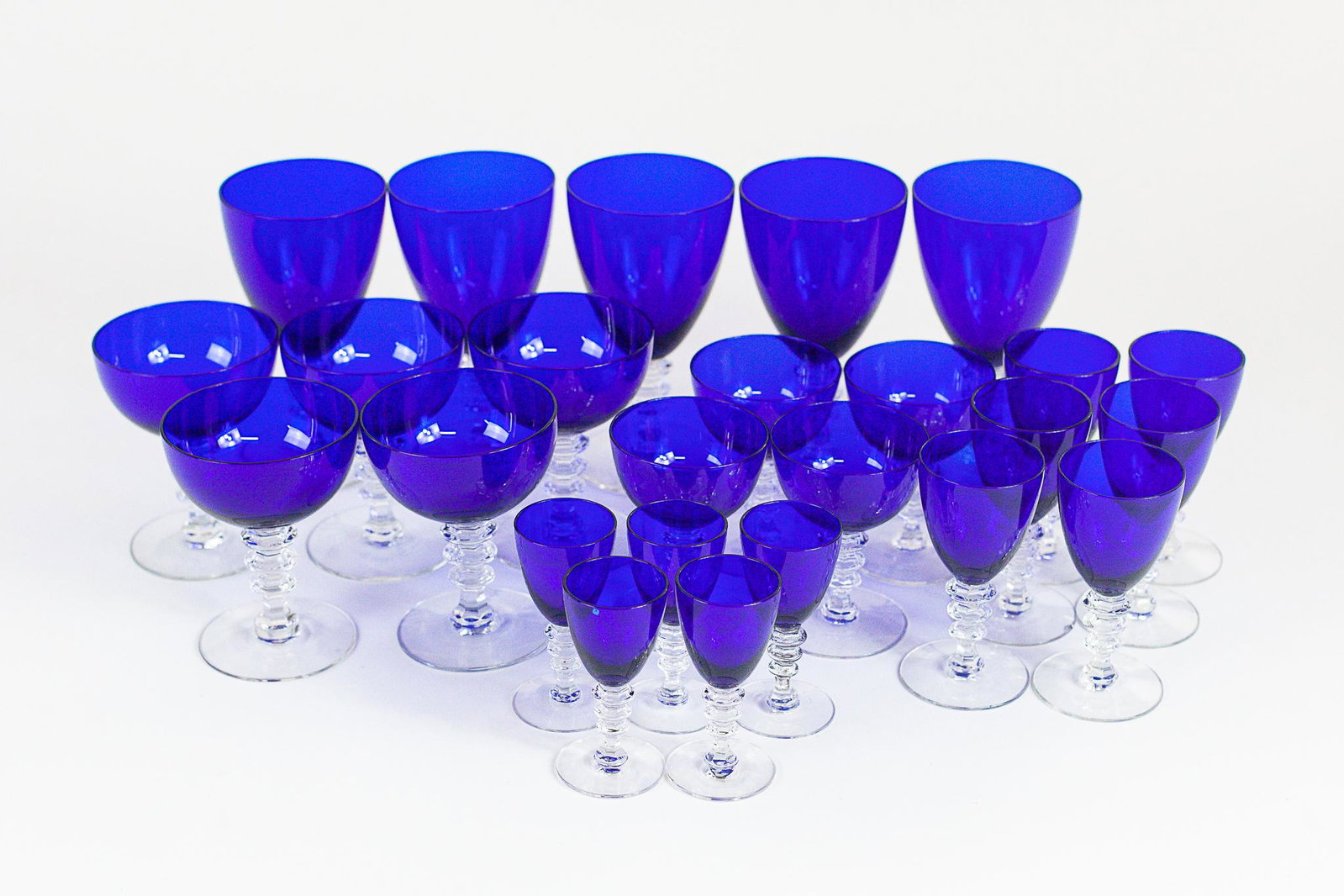 Collection of Cobalt Glass Stemware: Including 5 water goblets, 5 sherbert, 4 wine, 6 small wine and finally 5 cordial glasses. Each unmarkedwith clear bases in tiered pattern; tallest ht. 6.5".