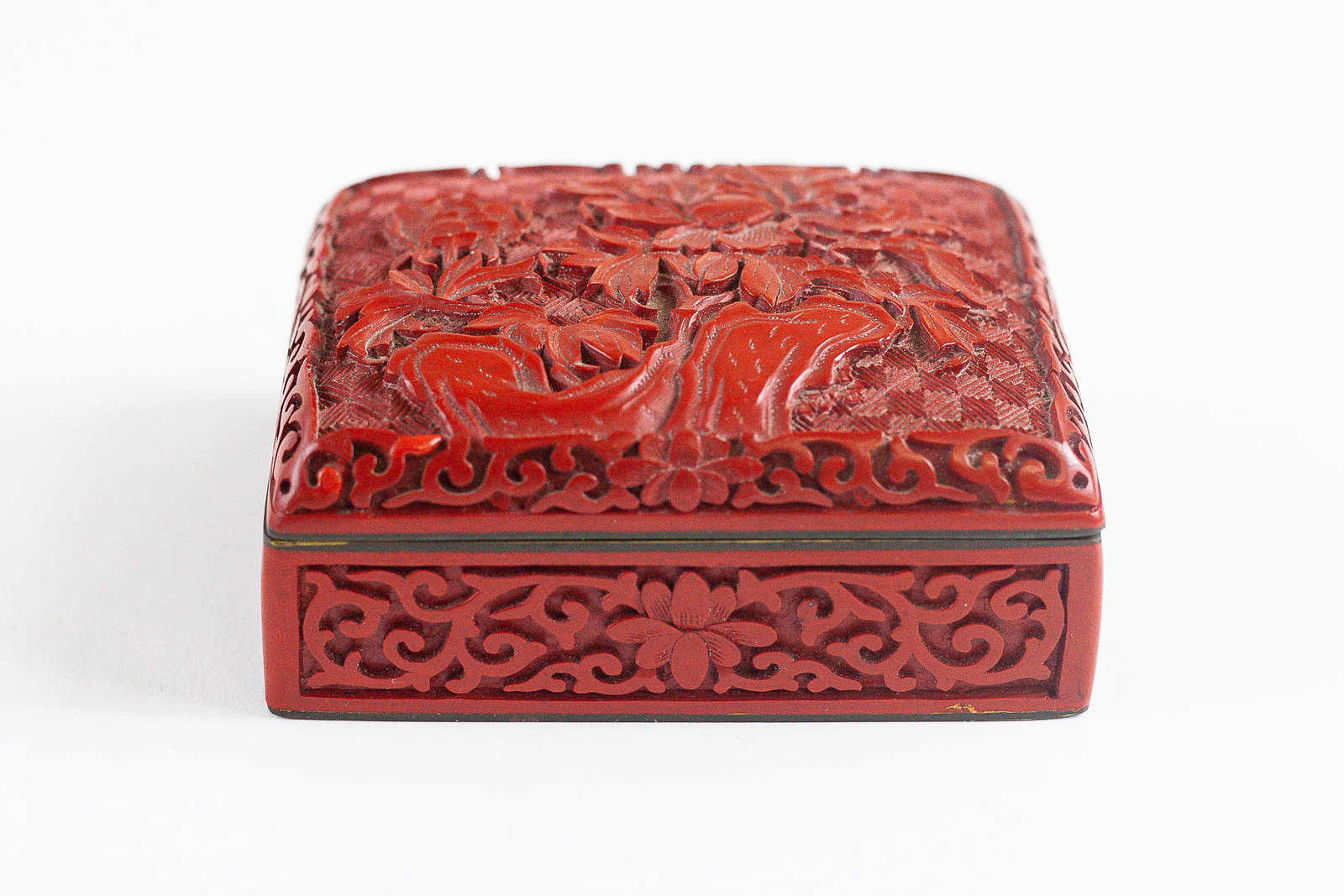 Floral Patterned Cinnabar Jewelry Box: Pattern includes two florals in relief on the top and centered florals on all four sides; 1.75" ht. x 4" wd. x 3" dp. Provenance</