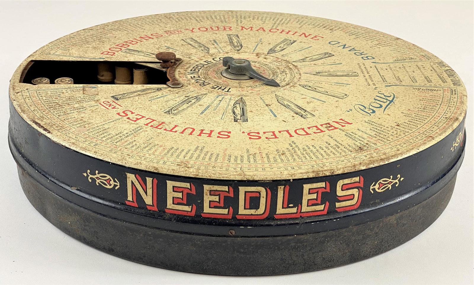 The Boye Co. Needle Store Display Case: A fabulous tin mechanical store display case for Boye Needle Company, with turning dial, and the interior containing wood cases of various sized needles; diameter 16".