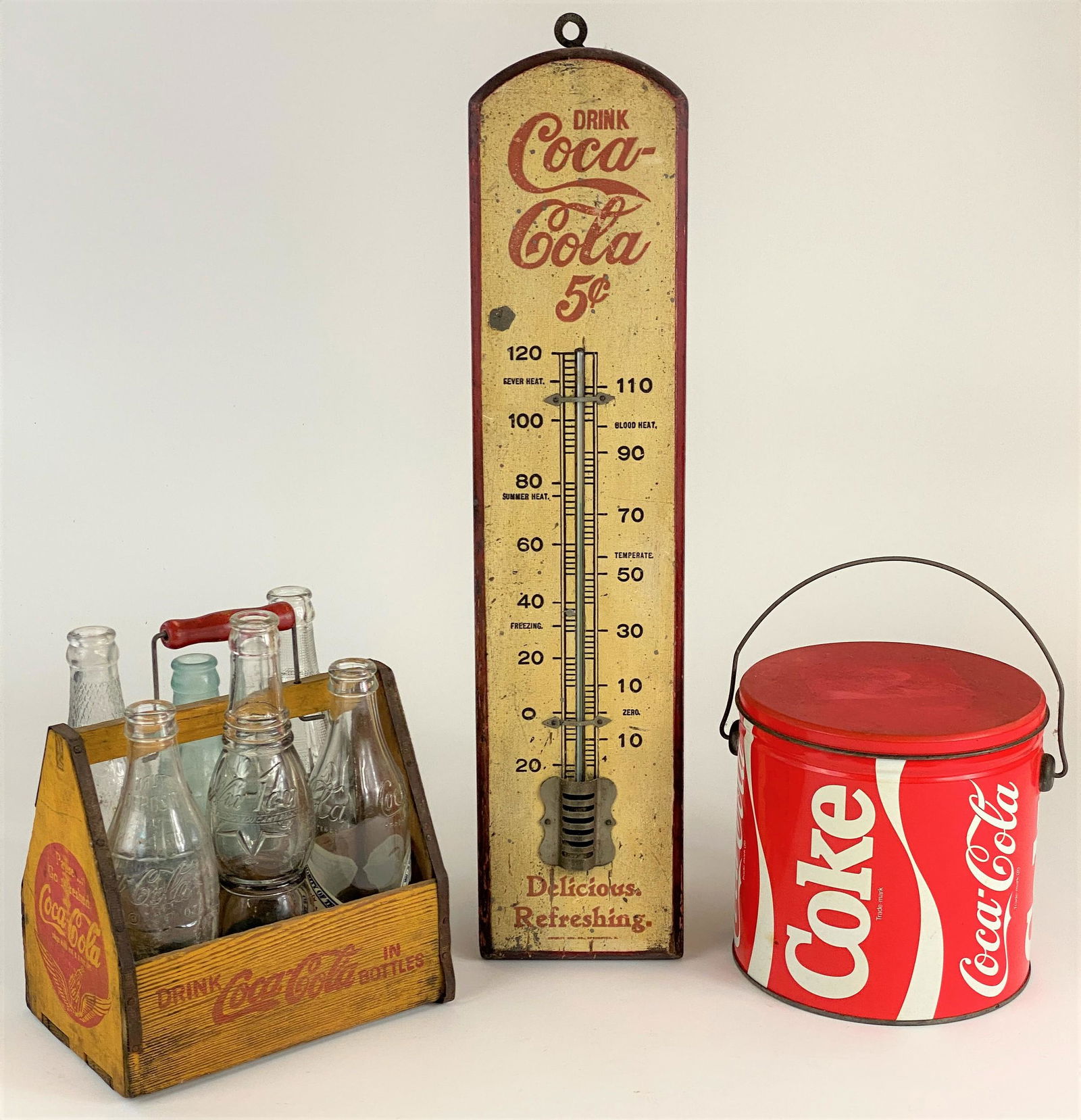 Coca Cola Thermometer, Six Pack Holder and Bucket: A great group of Coca Cola advertising, with an early 20th century thermometer, "Drink Coca-Cola 5 cent", a wooden holder with 2 old Coca Cola bottles, and 4 other bottles, and a tin Coca Cola bucket,