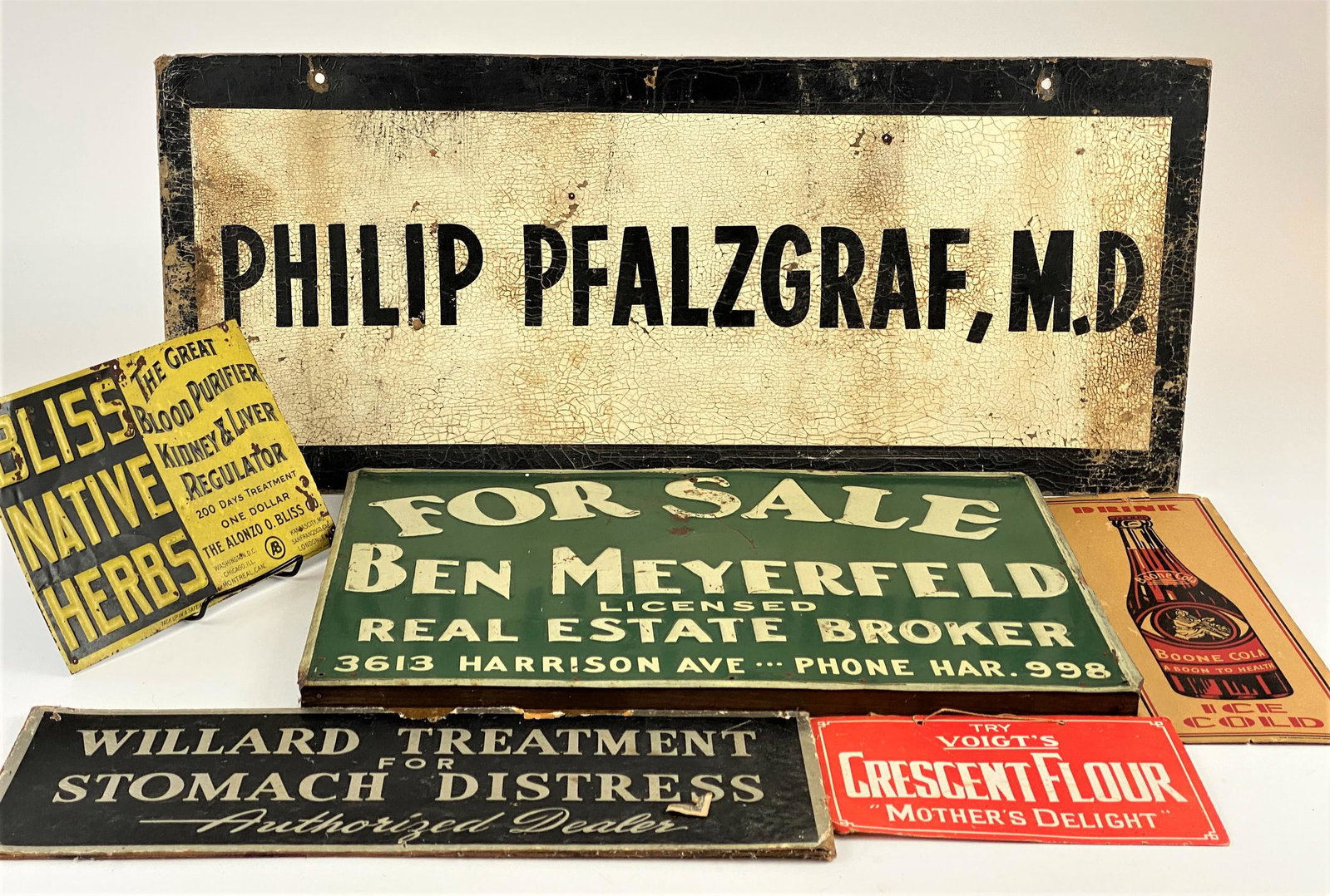 Group of Advertising Signs: Assembly of 6 advertising signs for various industries, including tin sign for "Bliss Native Herbs," tin "Ben Meyerfeld Real Estate" sign, and board signs for "Boone Cola," "Willard Treatment for Stom