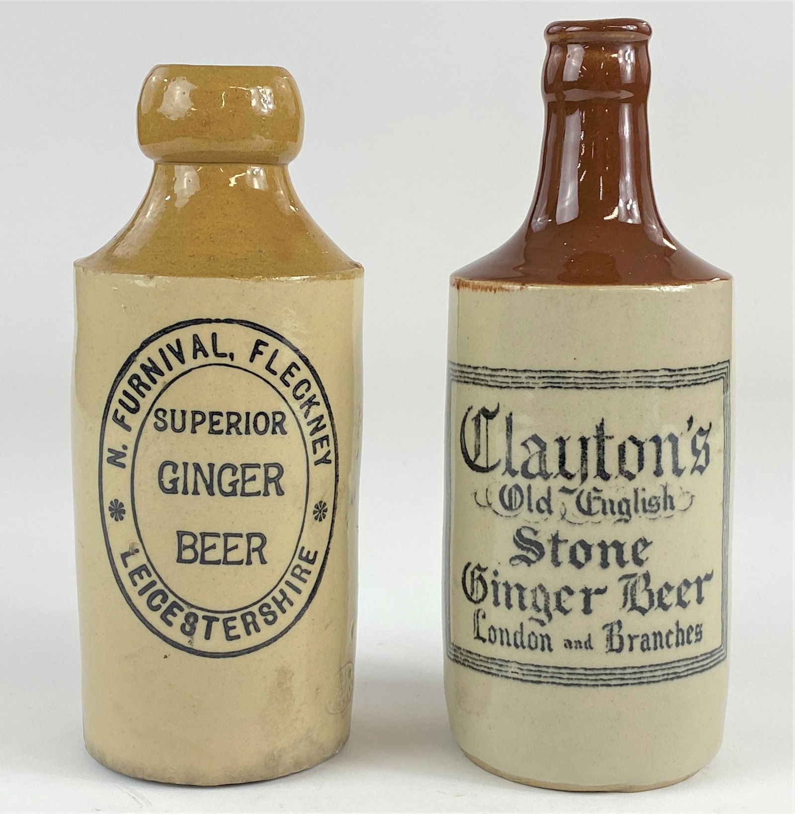 English Ginger Beer Stoneware Bottles: A pair of ginger beer stoneware bottles; "Superior" Ginger Beer brand and "Clayton's Old English Stone" ginger beer; both stamped "Bourne Denby 39"; ht. 7.5"
