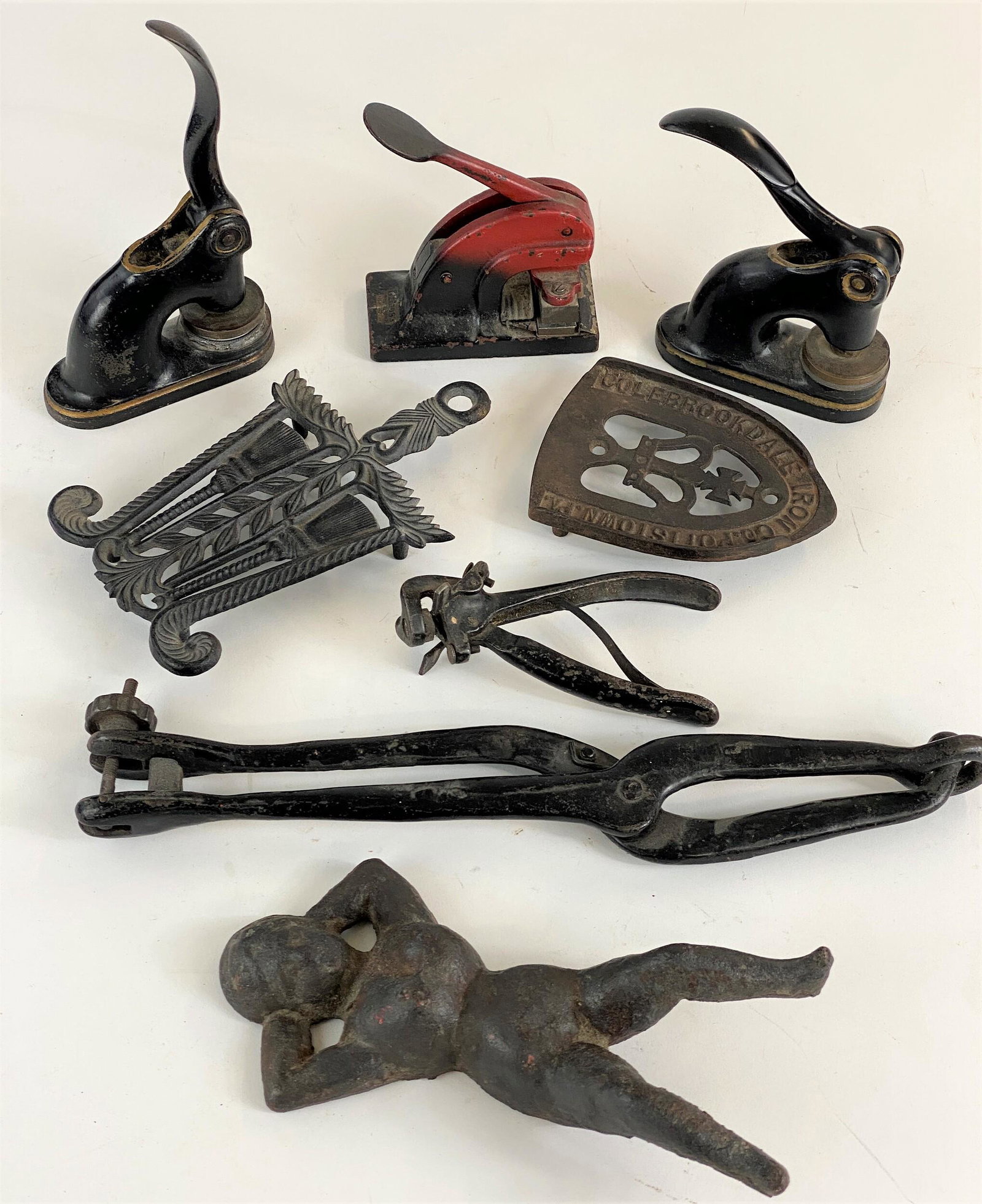 Group of Cast Iron Objects Including "Naughty Nellie": Eight cast iron antique items, including a "Naughty Nellie" boot jack, three embossers, and an iron rest, plus others pictured.