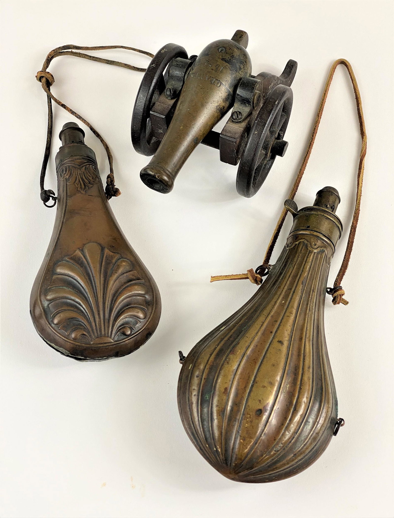 Pair of 19th Century Powder Flasks and Grant Cannon: A miniature cannon marked "Grant, 1872" and a pair of brass powder flasks, each 19th century; ht. of tallest 10".
