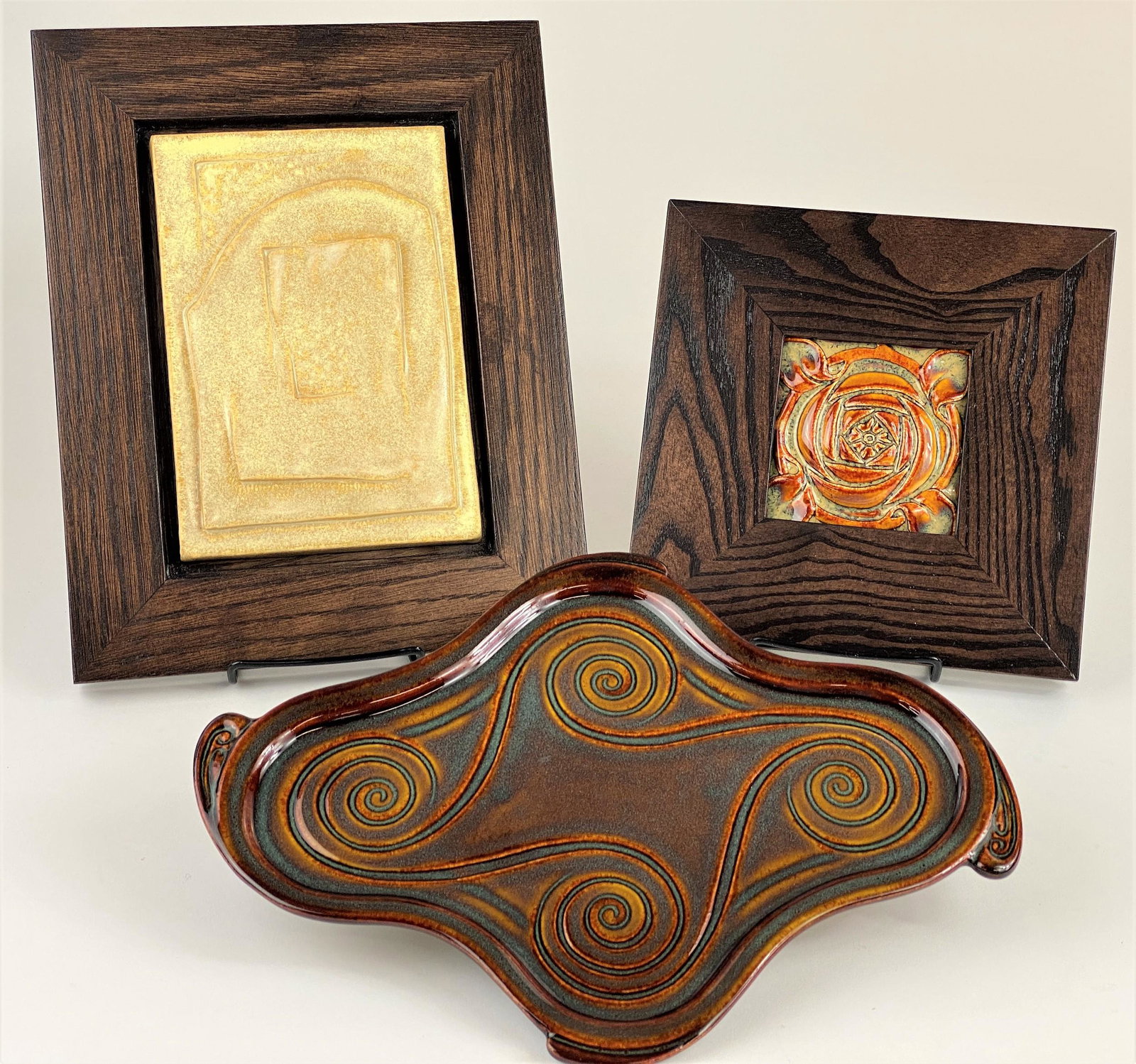 Three Boxed Contemporary Rookwood Pottery Examples: Including a framed tile, an abstract tile, also framed in oak, Arts & Crafts frame, and finally a designed tray, each example in original Rookwood box; largest frame 12" ht. x 9" wd.