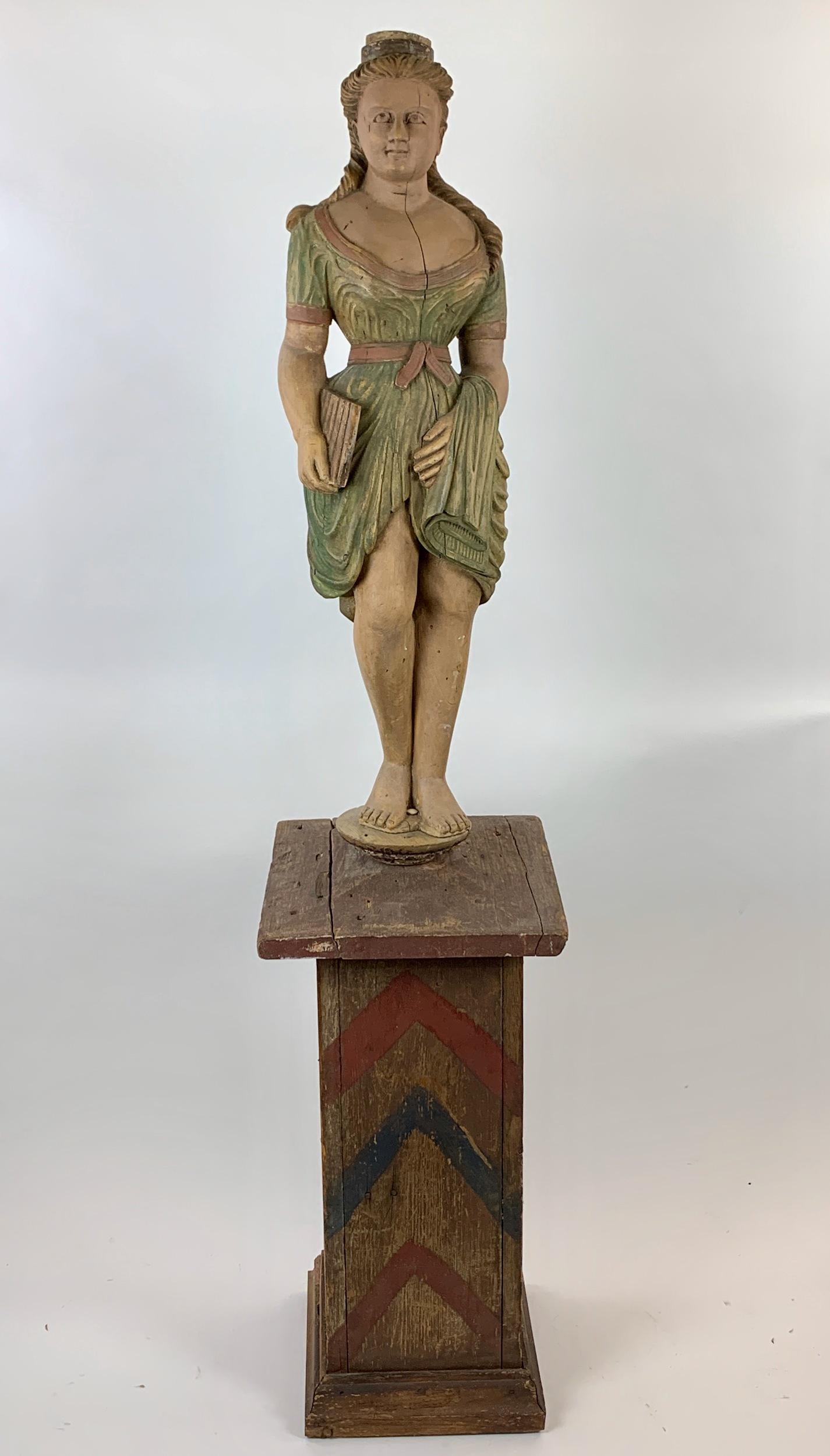 19th Century Folk Art Cigar Store Maiden: Late 19th century, a carved and painted cigar store figure of a maiden, with a robed figure holding batch of cigars, all atop a 19th century painted base; ht. 66".