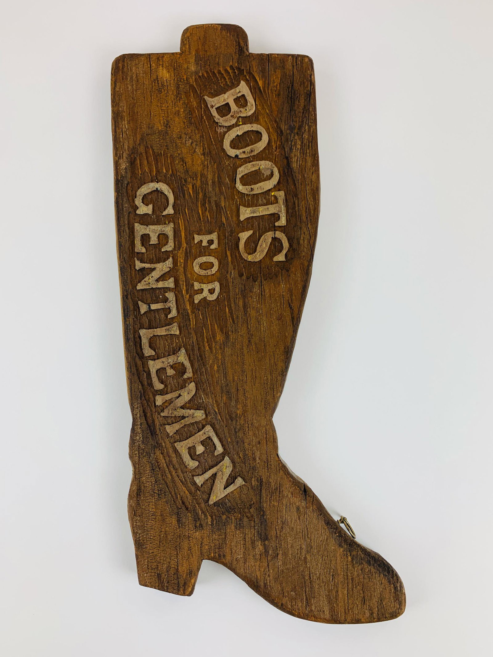 Handcarved "Boots for Gentlemen" Sign: A hand-scraped, carved advertisement promoting "Boots for Gentlemen," with the letters in relief and the whole of the sign carved in the shape of a boot; 23" ht. x 9.5" wd.