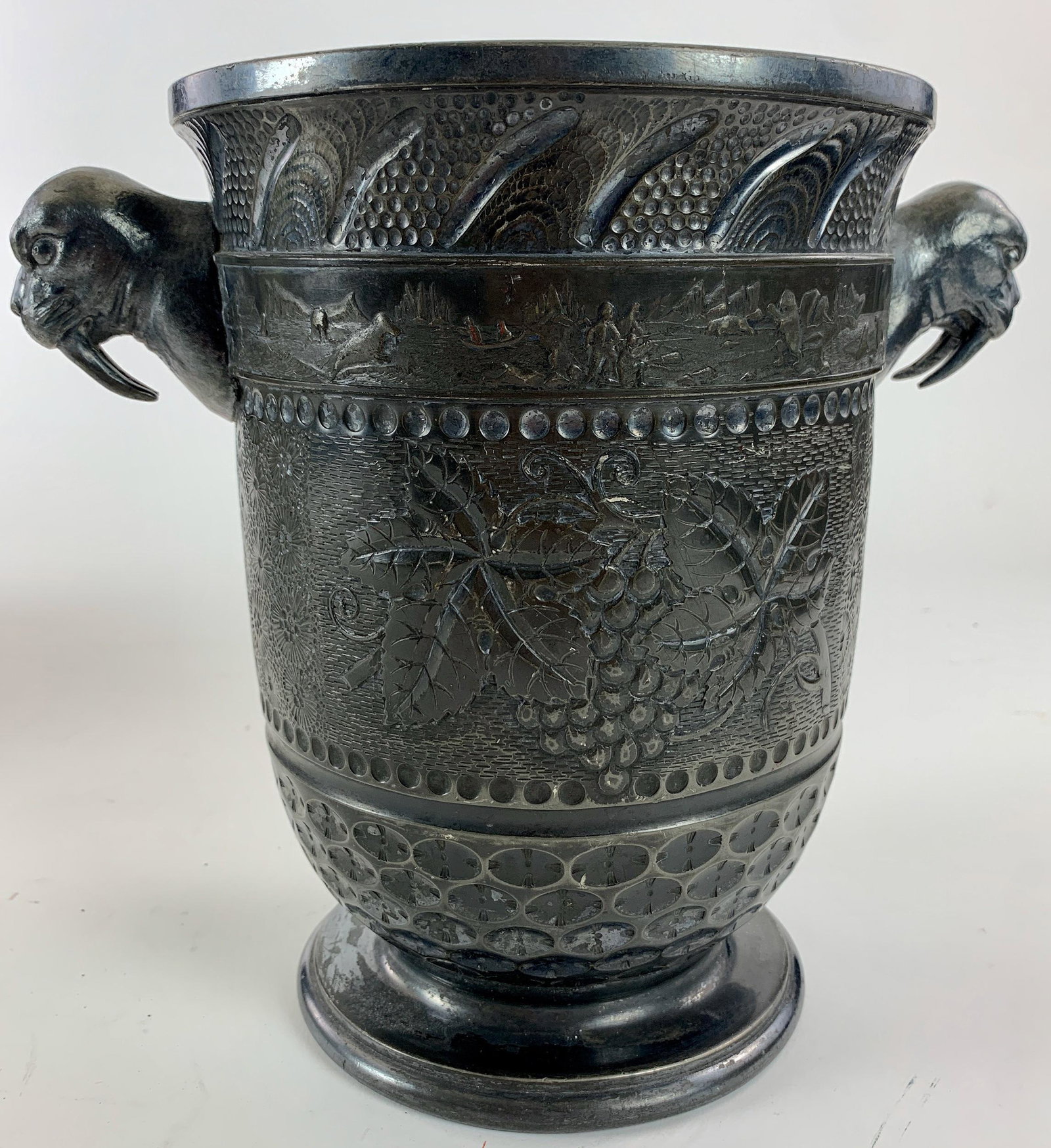 A Fine Rogers Bros. Silverplate Trophy with Walrus and: An interesting silverplated trophy or wine cooler, with a fine surrounding scene toward the rim depicting hunt scenes in relief, as well as a pair of walrus handles; ht. 9.5".