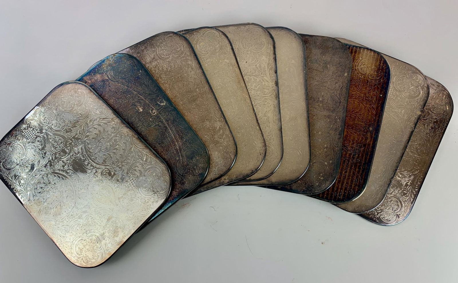 Silverplated Overlay Cavalier Trays: A set of ten "undertrays" or placemats for the table, with incised decoration, each with sticker label to underside felt; each 14" x 10.75".