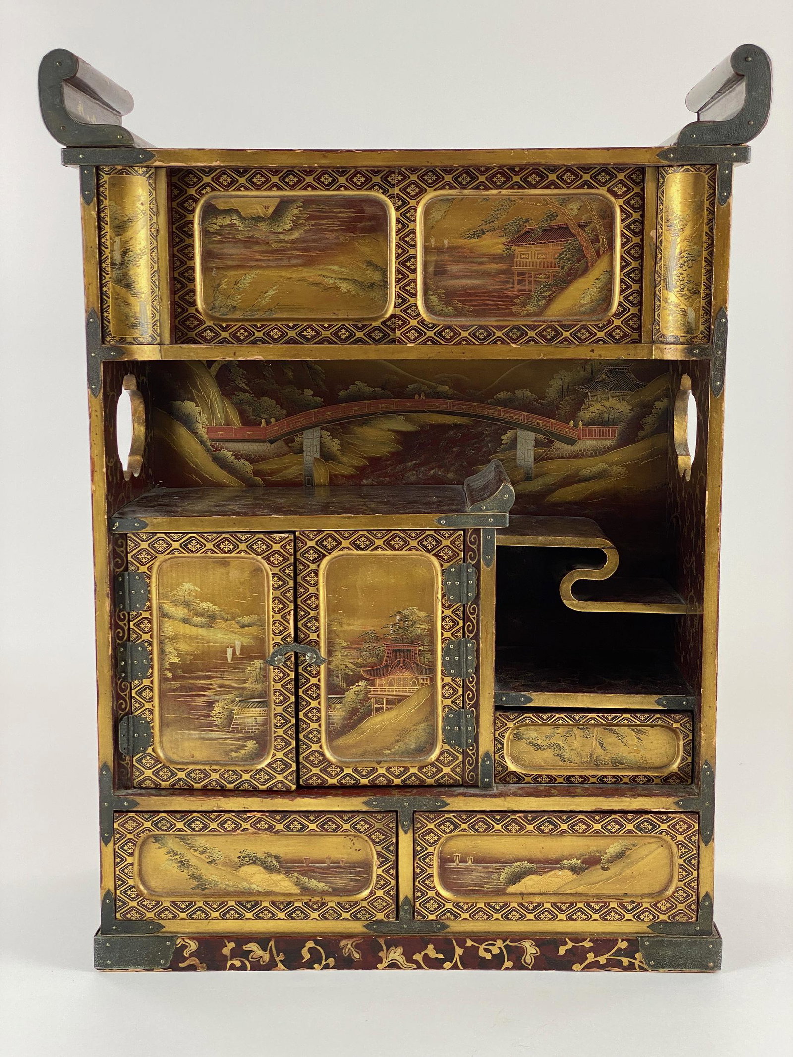 A Japanese Lacquer Shodana, Edo Period: An exceptionally fine lacquered shodana (display cabinet), 19th century. With gilt scrollwork throughout the sides, crest and shelves, and various doors and drawers containing meticulously lacquered r