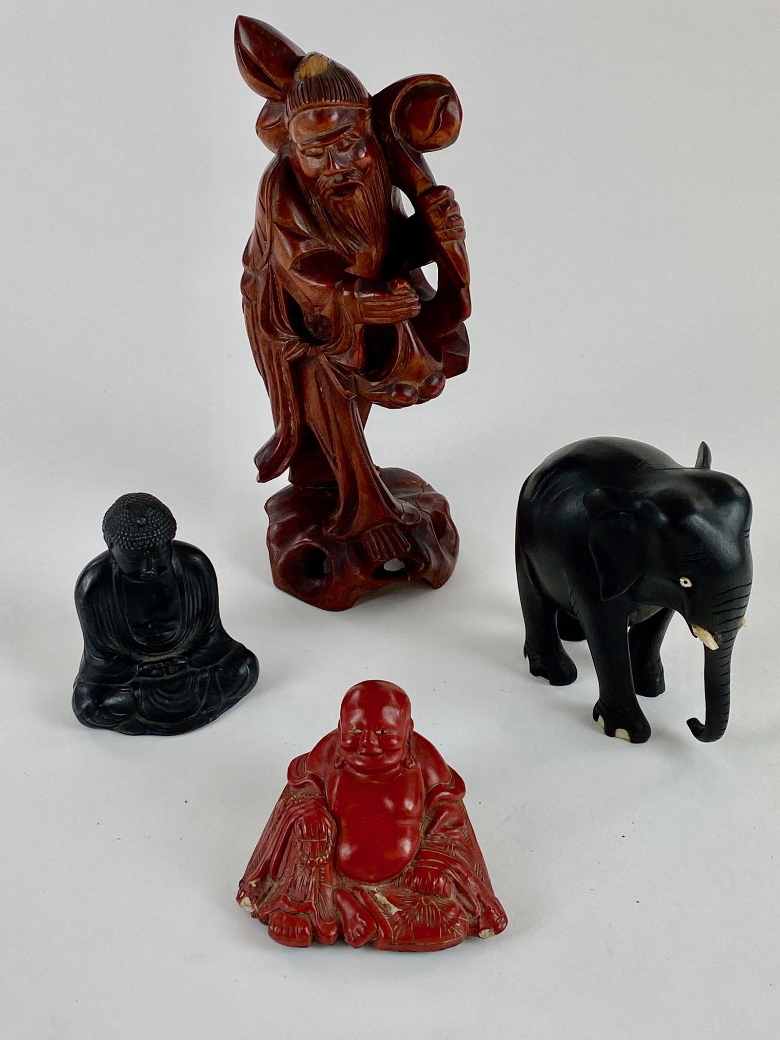 Chinese Carvings and Ink Figure: A group of four sculptures, including a carving of a god, an ink Buddha, signed to underside, a cinnabar Buddha, and finally an elephant carving; ht. of tallest 8.5".