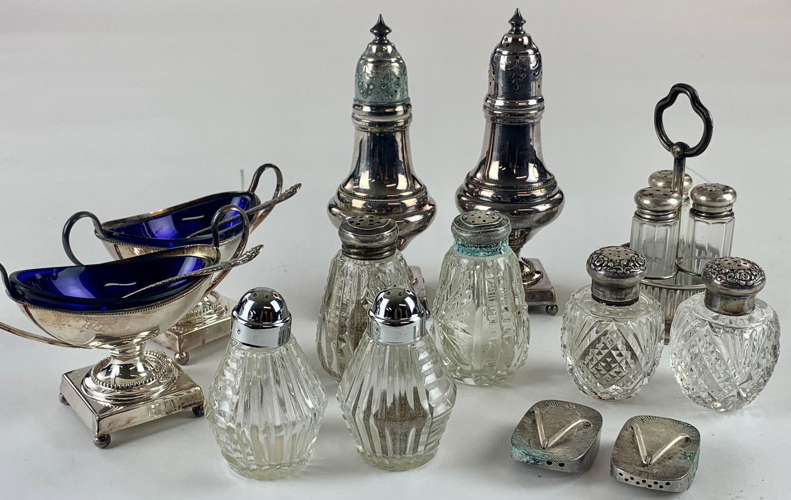 Collection of Salt & Peppers, Some Sterling: A group of 7 pairs (one is a triple) of salt and pepper dispensers, including a pair with glass inserts and spoons, a small pair of 950 silver sandal form shakers, a larger pair of plated shakers, and