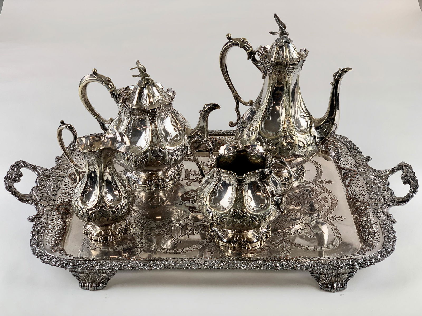 JS&S Silver-plated Tea Set with Tray: An etched designed 4-piece tea set, each with hallmarks of JS&S, a beaver, crown, and letter, silver-plated. Pair of teapots with hawk finial, as well as an unmarked tray; Tray size 27.5" x 16.5", ht.