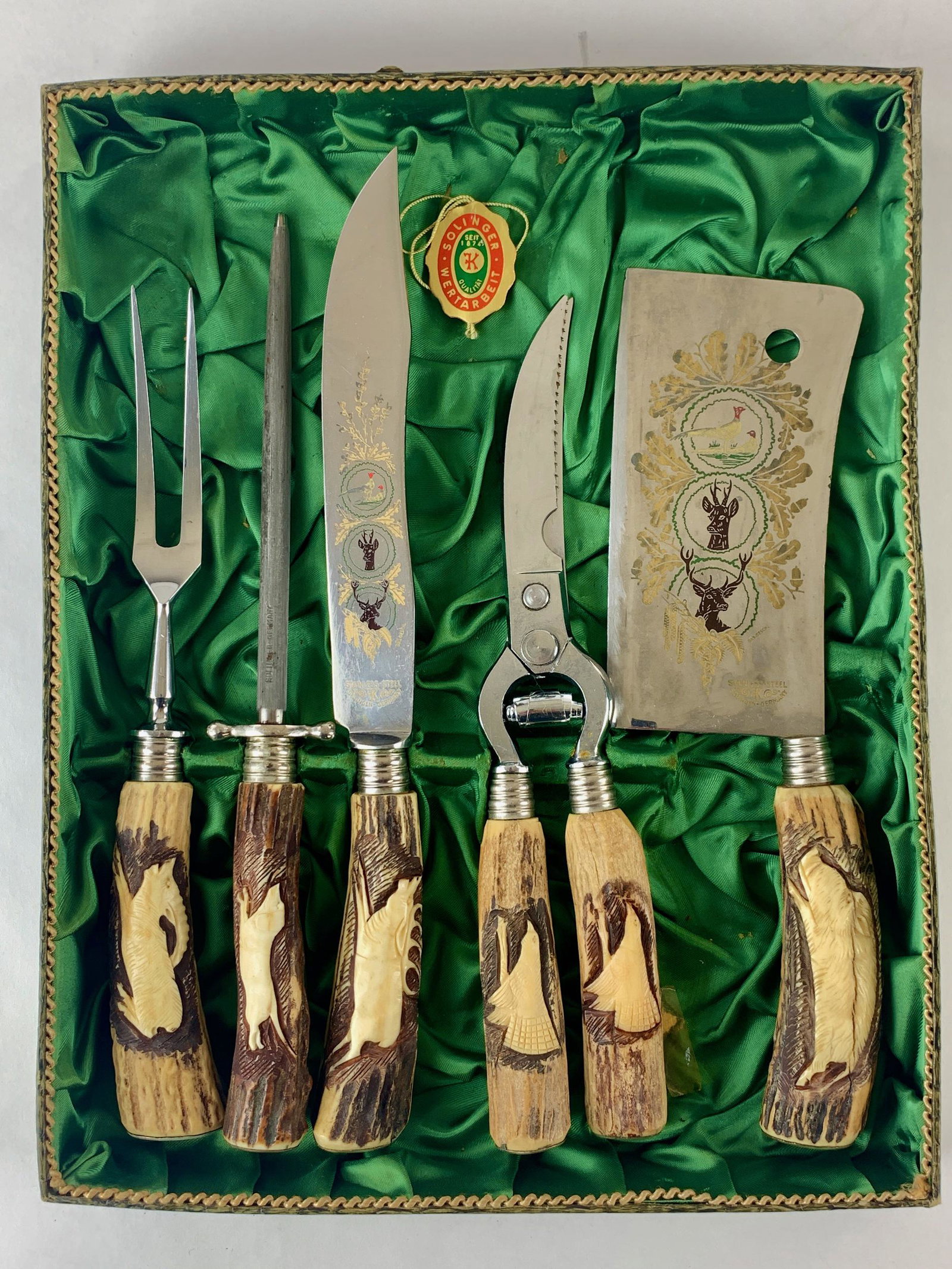 Solingen 5 Piece Carving Set in Box: A Solingen, Germany boxed meat carving set, each with carved antler handles and etched blades, including scissor, chop blade, knife, fork and poker. Box 14" x 11". From the Estate of Harold and Miriam