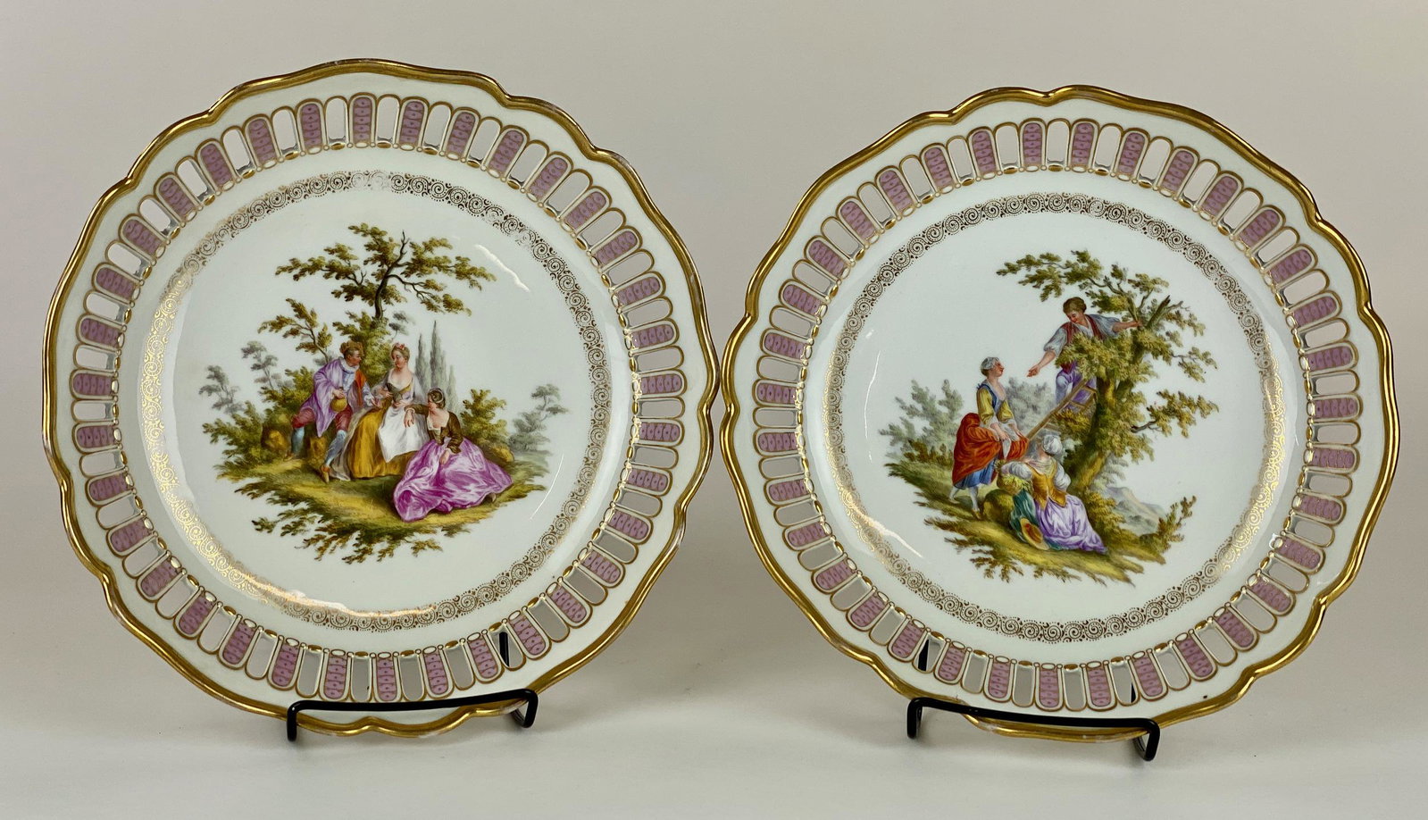 Pair of Meissen Plates with Scenic Reserves: A pair of Meissen reticulated plates, each with gilt interior rim and painted scenes, one courting and the other tree picking; diameter of each 9.75". From the Estate of Harold and Miriam Prigozen, Da