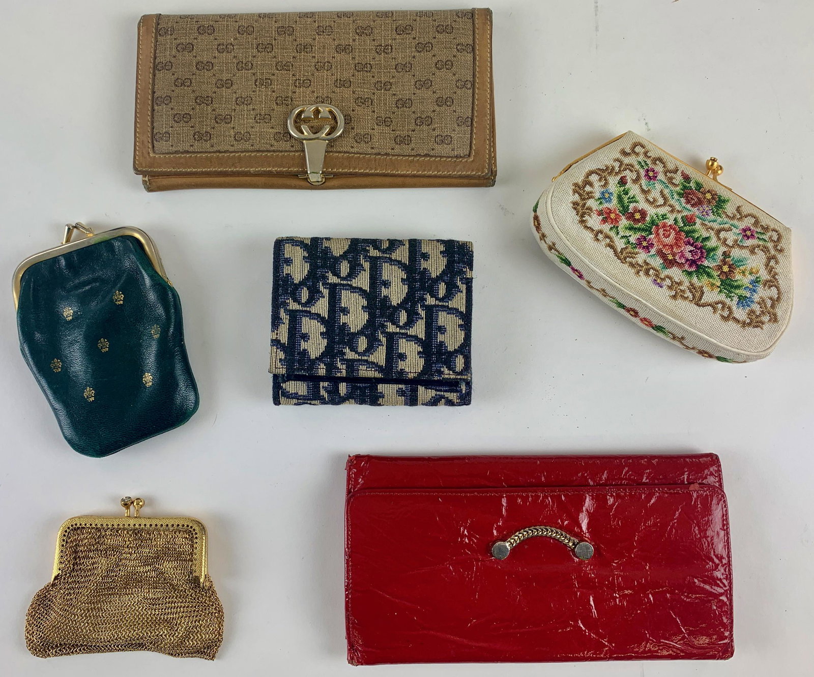 Collection of Designer and Vintage Wallets: Including a Bond St. marked leather wallet, a Dior wallet, a Gucci wallet, a needlepoint example, a green leather coin purse with fleur de lis, and finally a gold toned mesh coin purse. Largest 7" x 3
