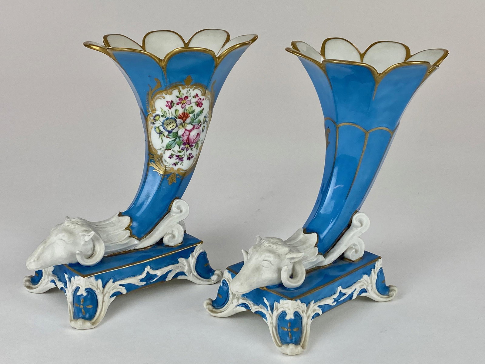 Pair of Pitt Petri (France) Porcelain Vases: A set of decorative vases, with handpainted detail and gold accents, with a figure of a ram at the base of each. With blue and bisque glaze. Ht. of each 7" From the Estate of Harold and Miriam Prigoze