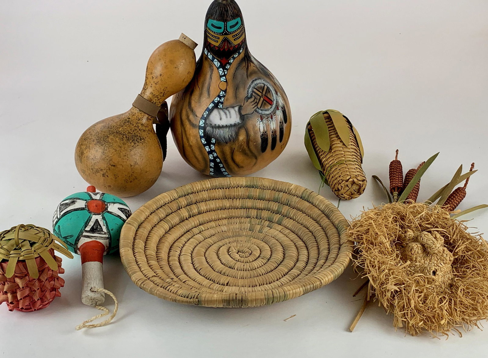 Southwestern Gourds, Baskets, and Ephemera: A group of harvest material, including a painted and incised large gourd, signed and dated to underside, a painted rattle, 4 corn stalk works of art, another gourd drinking vessel, and finally a baske