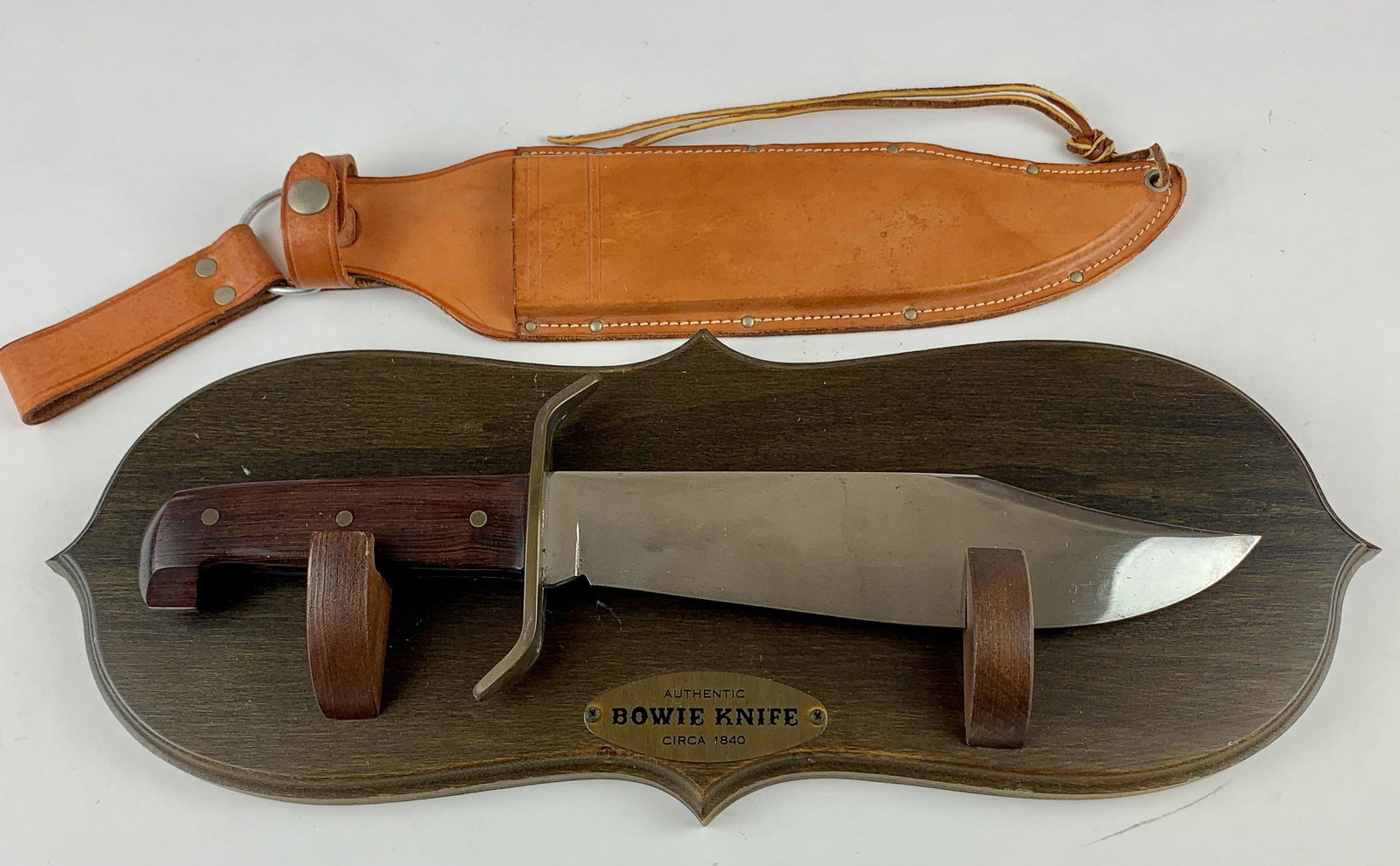 Western Bowie Knife with Sheath and Plaque: Large vintage Bowie knife with wood grain handle. Marked to guard "WESTERN, Boulder, Colo, U.S.A." and "W49." With tan leather sheath and wooden hanging plaque. Knife measures 15" long in total, blade