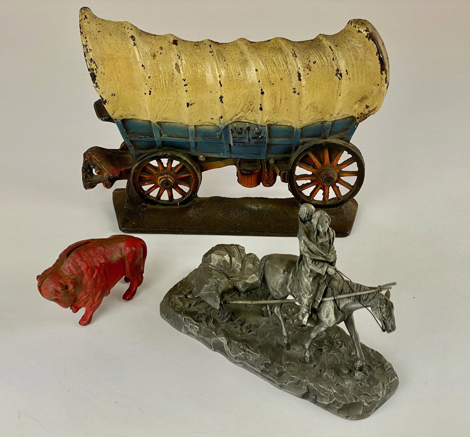Painted Iron Wagon Doorstop, Bank and Sculpture: A cast iron doorstop of a wagon, handpainted. Also a buffalo cast iron coin bank, and a pewter sculpture. Doorstop marked to rear "Copyright 1930." 8.5" ht. x 11" wd.