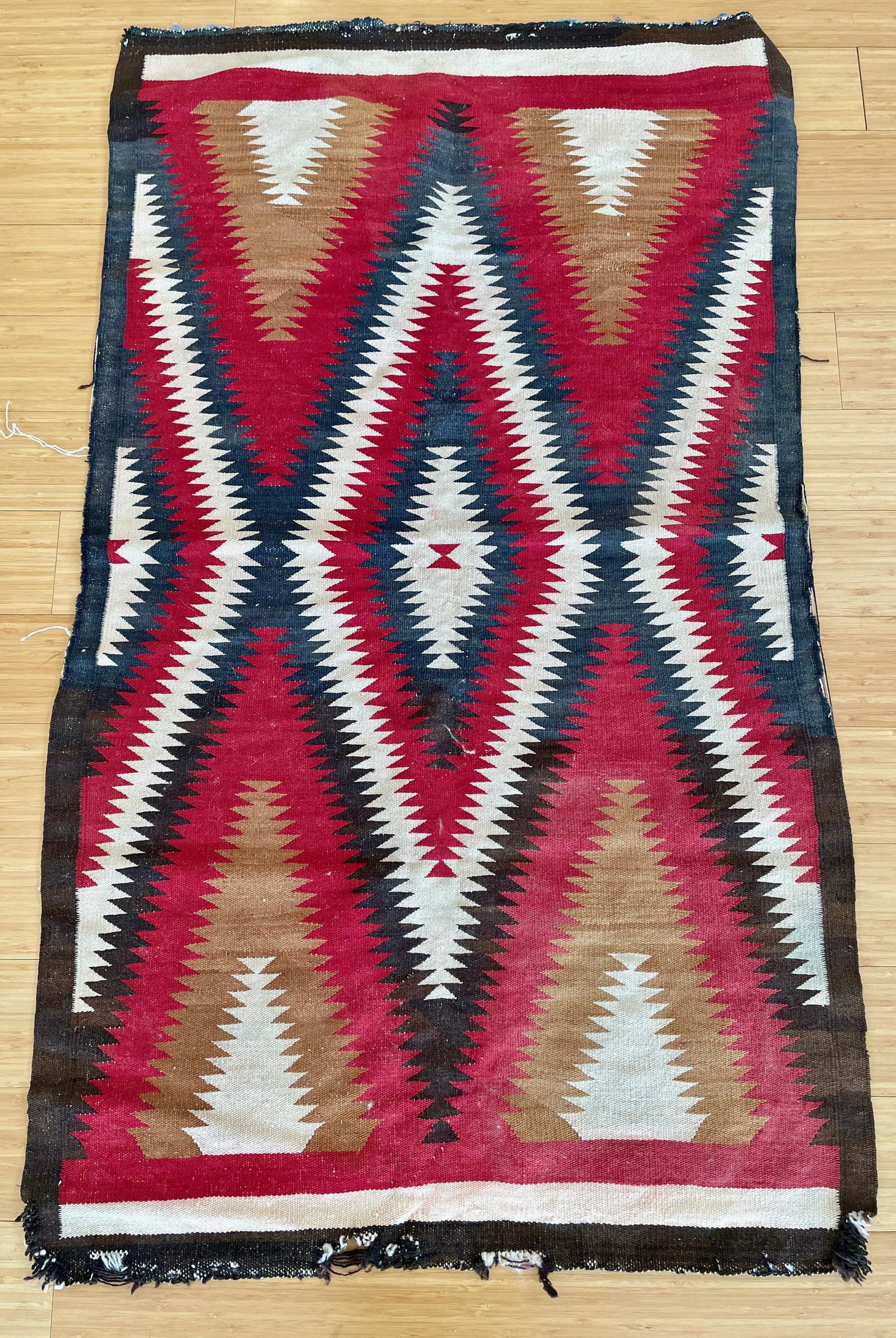 A Navajo Prayer Rug: With traditional red, black, brown and cream coloring and diamond pattern. Size: 56" x 34"