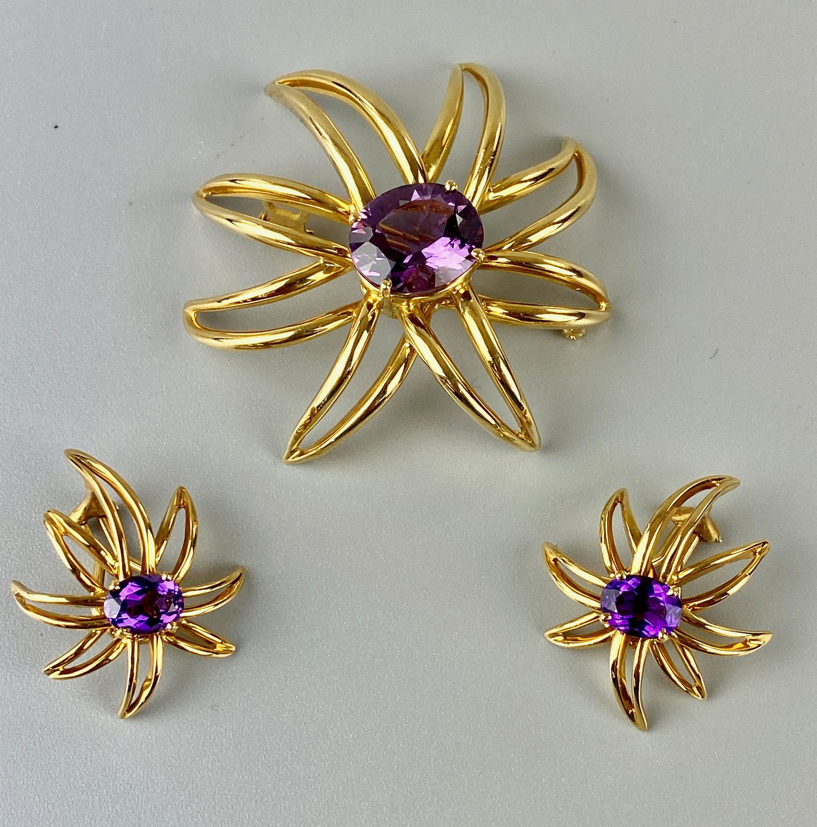 1994 Tiffany and Co. 18 Karat Gold Earrings and Brooch: With amethyst stones in center with good coloration. Firework design. 34.8 grams total Lifetime collection of Carol and Robert (Rob) Kane, Oxford, OH.