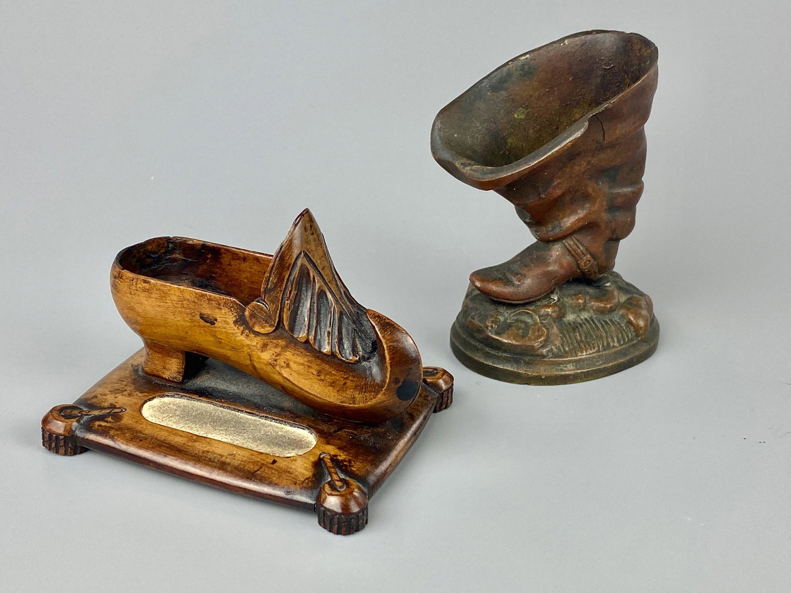 Pair of Boot Related Matchsafes: One carved from walnut in clog fashion and the other cast.