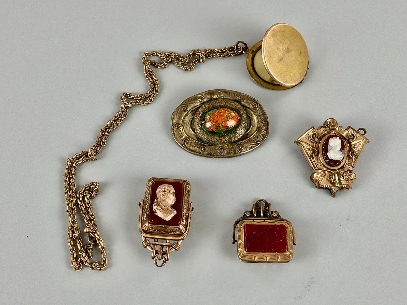 Group of Lockets, Cameos, and Hair Pendants: Including a cameo pendant with interior for hair or photograph, another stone example of the same, a cameo pendant with gold filled case, a stone pendant, and finally a photograph locket necklace.