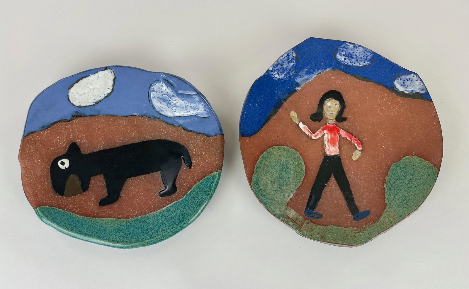 Minnie Adkins & Tess Little Chargers: A pair of decorated pottery chargers, each by Minnie Adkins and Tess Little, Kentucky folk artists, one with an animal and the other a figure. Largest diameter 10"