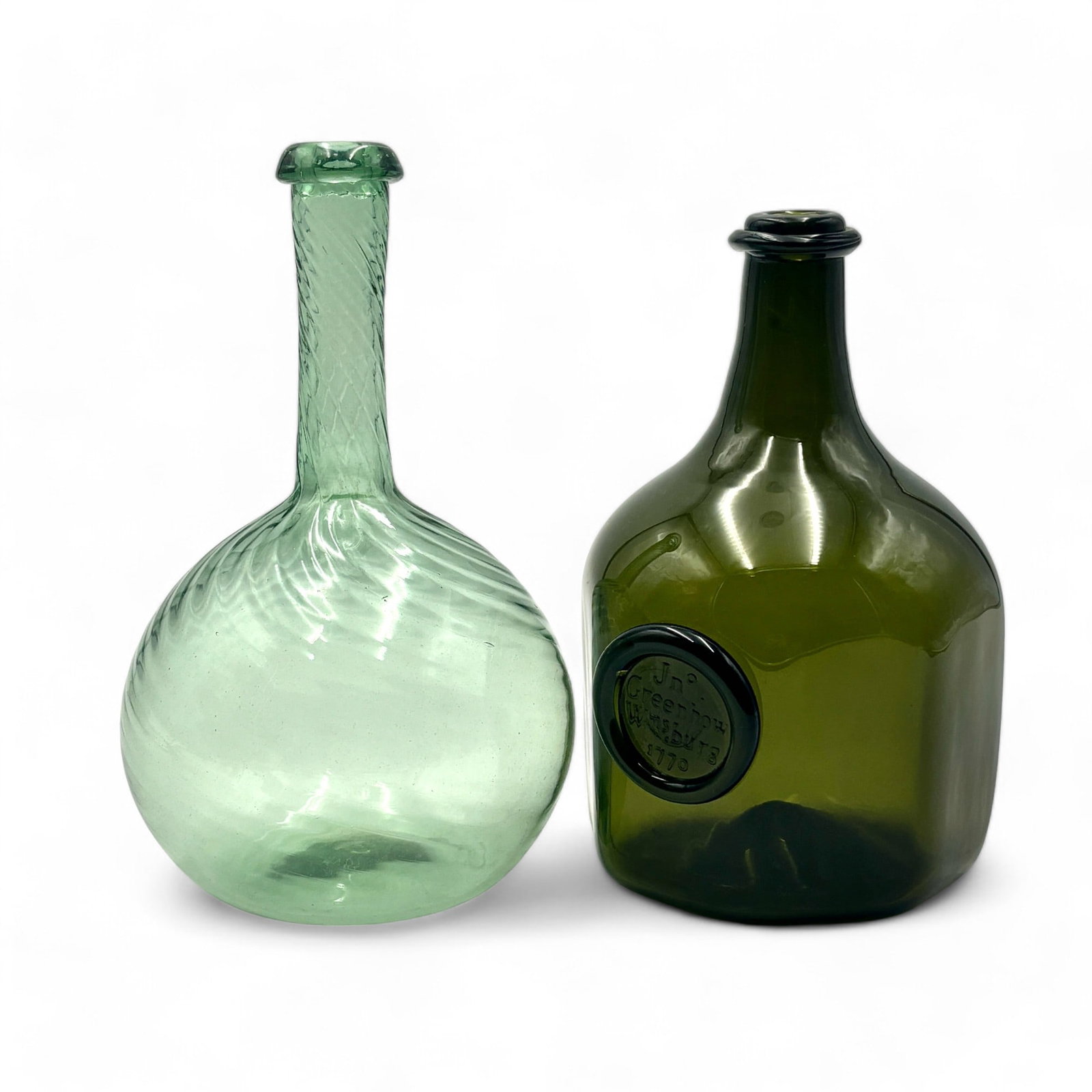 Pair of Glass Reproduction American Bottles: Including a 20th century Zanesville style swirl bottle, as well as a 20th century Greenhow colonial bottle. Tallest ht. 8". The green bottle is inscribed on the bottom, appears to be "KPK" and "FV83"