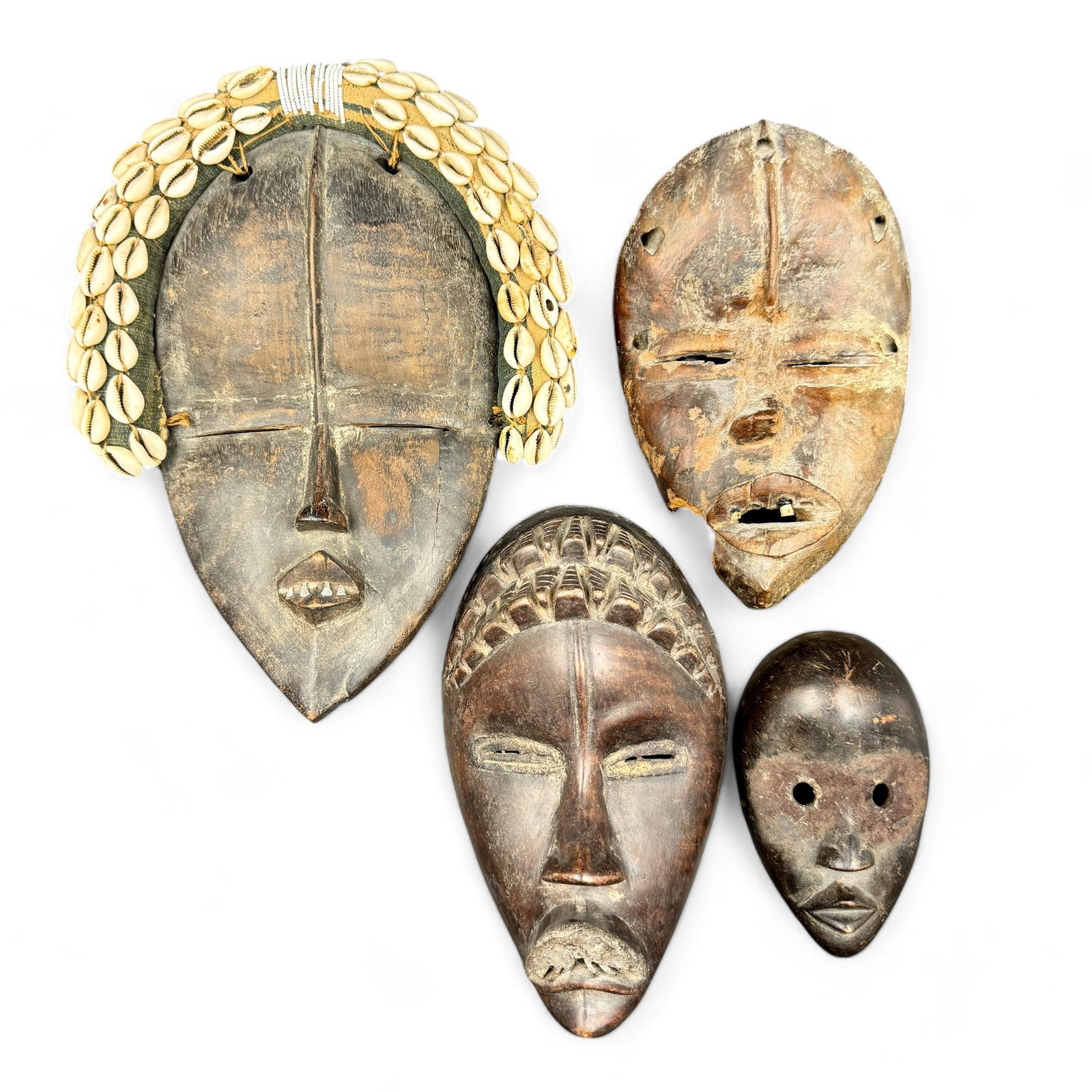 Group of African Masks: Including examples from the Ivory Coast, Dan Masks. One with shell and bead decoration, two with teeth. Largest size: 12" ht. x 9" wd.
