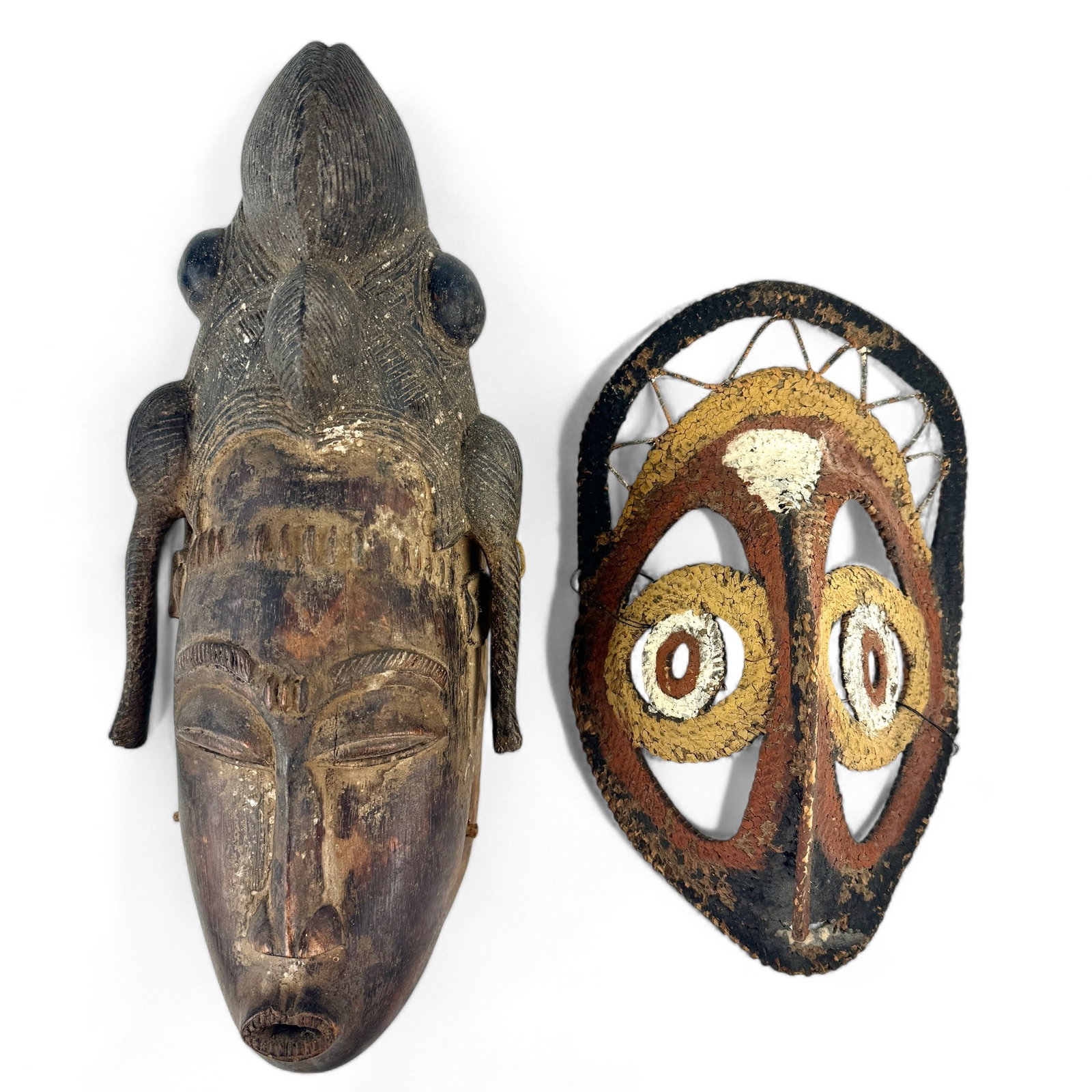 Pair of Masks, African and Papa New Guinea: A Papa New Guinea woven mask with color decoration and a Baule mask, Ivory Coast. Tallest height: 14.5"