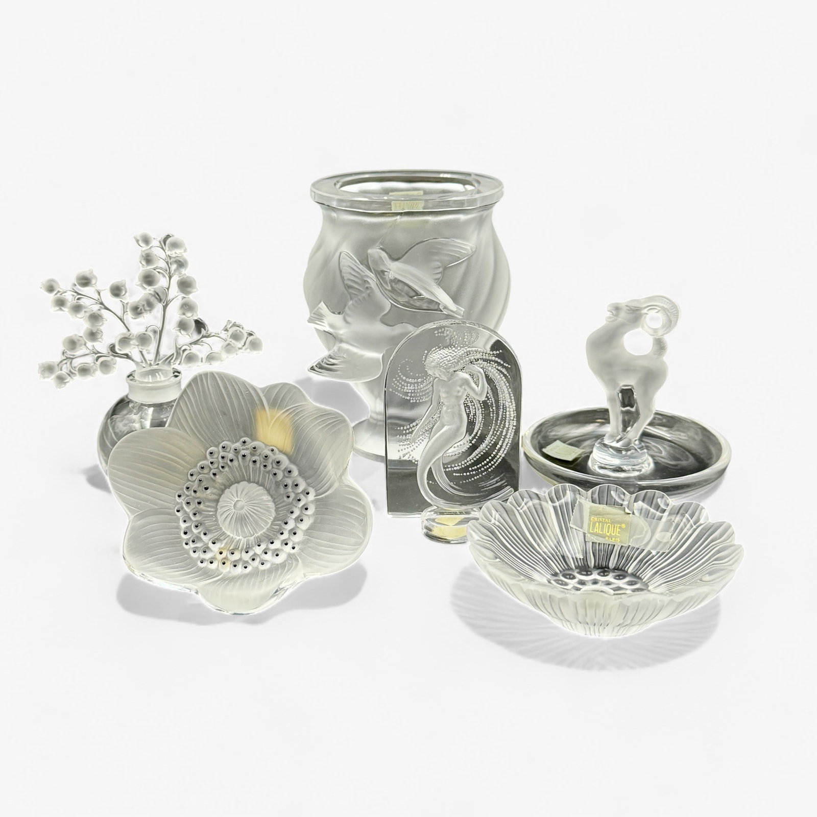 Collection of Lalique Accessories: Six pieces of Lalique glass, mostly tabletop accessories, with some clear glass and some opalescent. Including a small vase, candy dishes, decorative flower, perfumer and nude plaque. Tallest is the v
