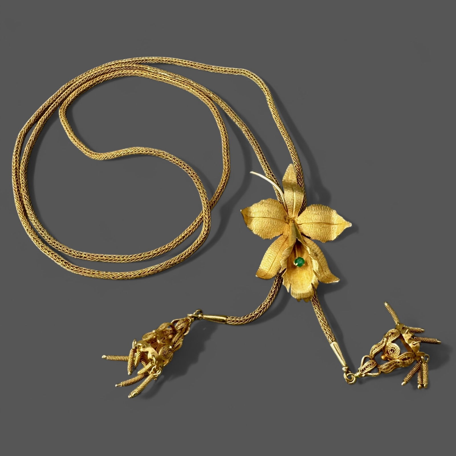 Ladies 18K Gold Floral Necklace with Inset Emerald: Ladies 18k gold necklace with multi-faceted design featuring floral to center with small inset emerald. Chain drops down to two 18K gold filigreed crowns at base. Total weight .99 troy ounces