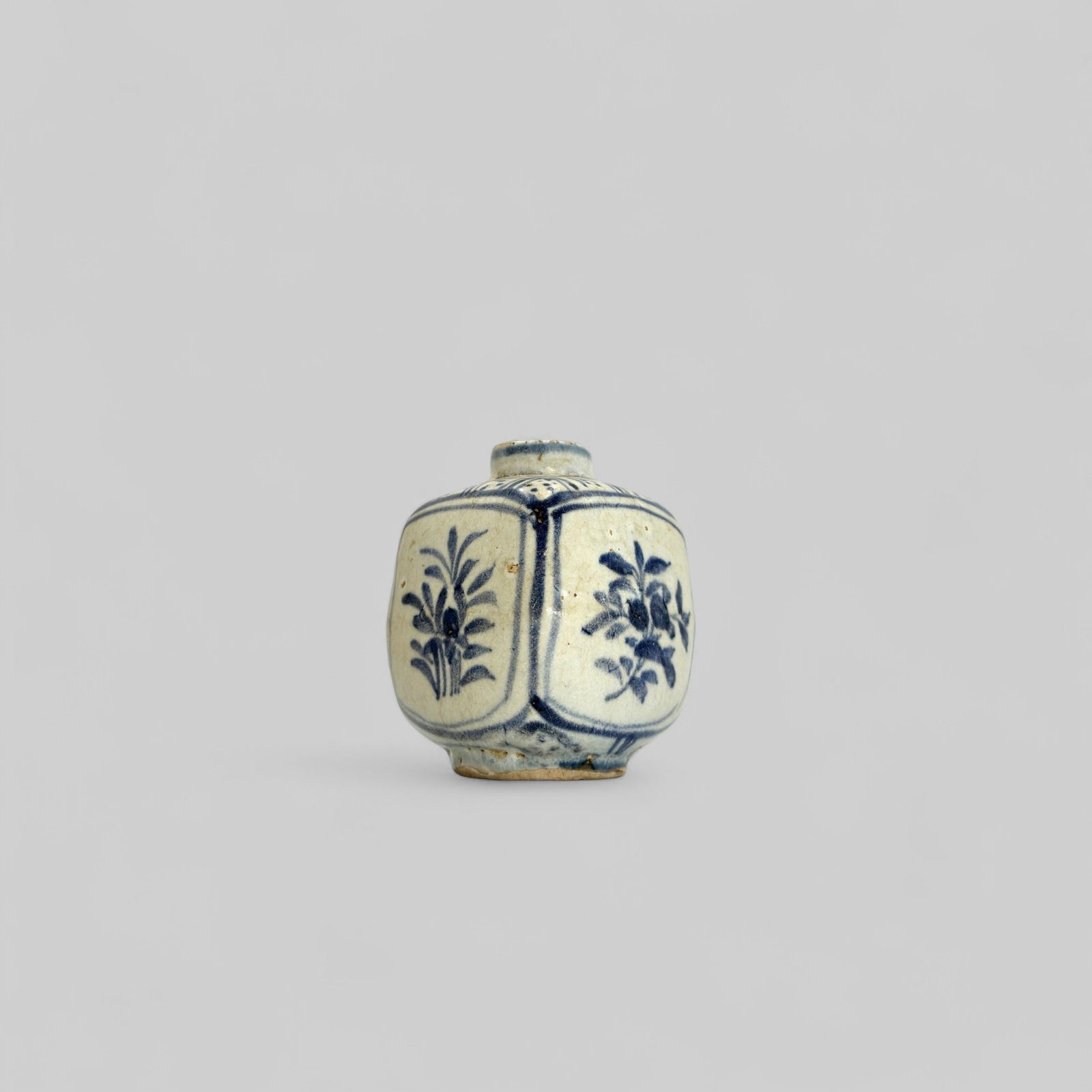 Porcelain Jar, Yuan: A jar of rectangular shape has a cylindrical neck, a circular foot, and a flat base. The sides are decorated with alternating panels of lotus and floral sprays, painted in a grayishblue color. A diape