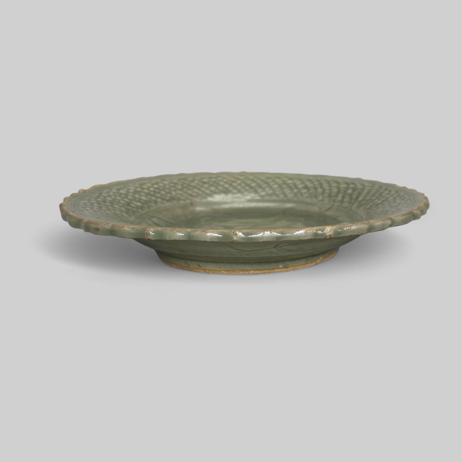 Longquan Celadon Scalloped Dish: Song or Yuan dynasty, with detailed incised interior and scalloped rim. Diameter 9.5".PROVENANCEPrivate Midwestern Collection, acquired from sources in Southeast Asia, ca. 1965-1975.