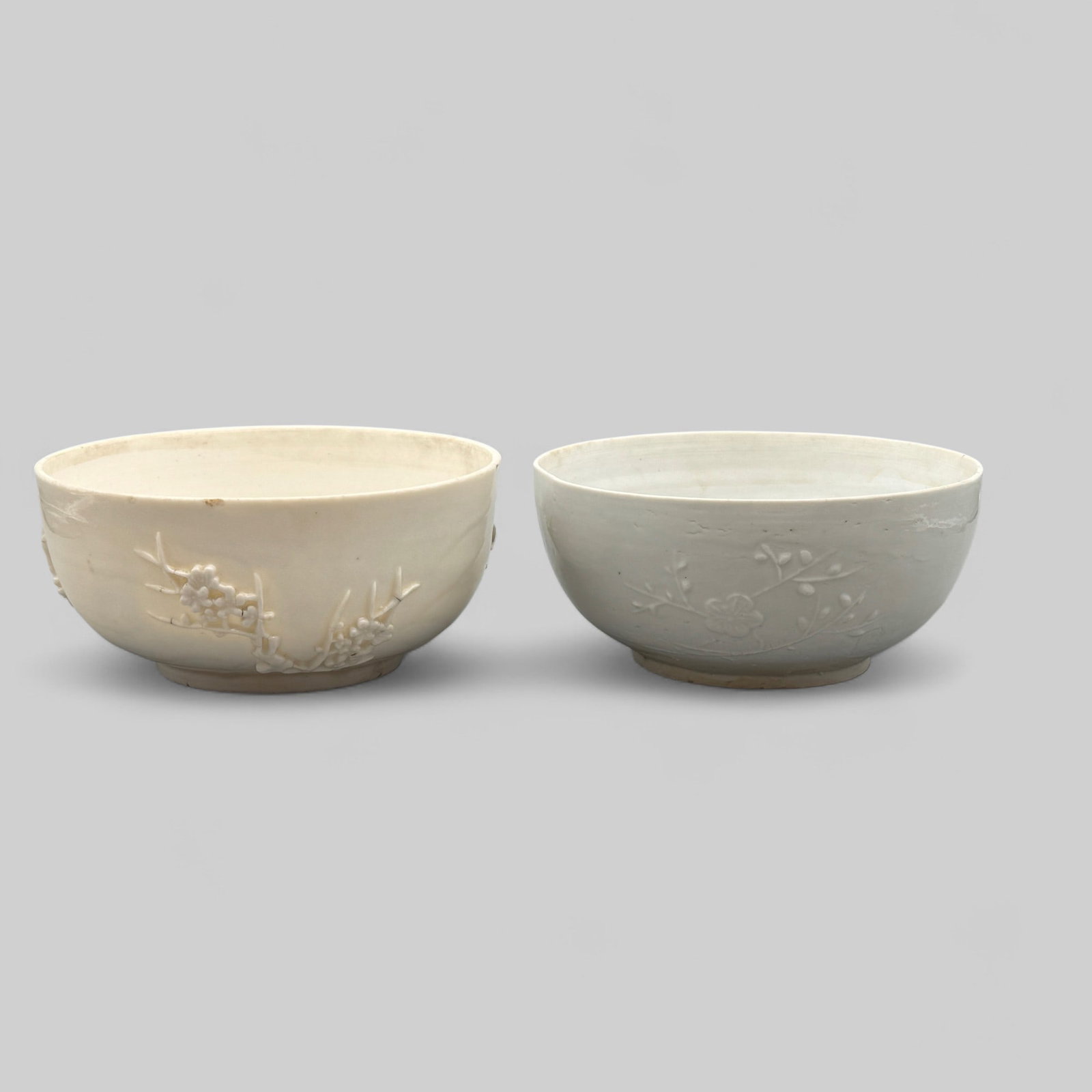 Pair of Dehua Bowls: A pair of Yuan/Ming Dehua ware bowls, each with formed exterior body to reveal floral branches. Ht. of each 3.75", diameters 7.75". PROVENANCE Private Midwestern Collection, acquired from sources in S