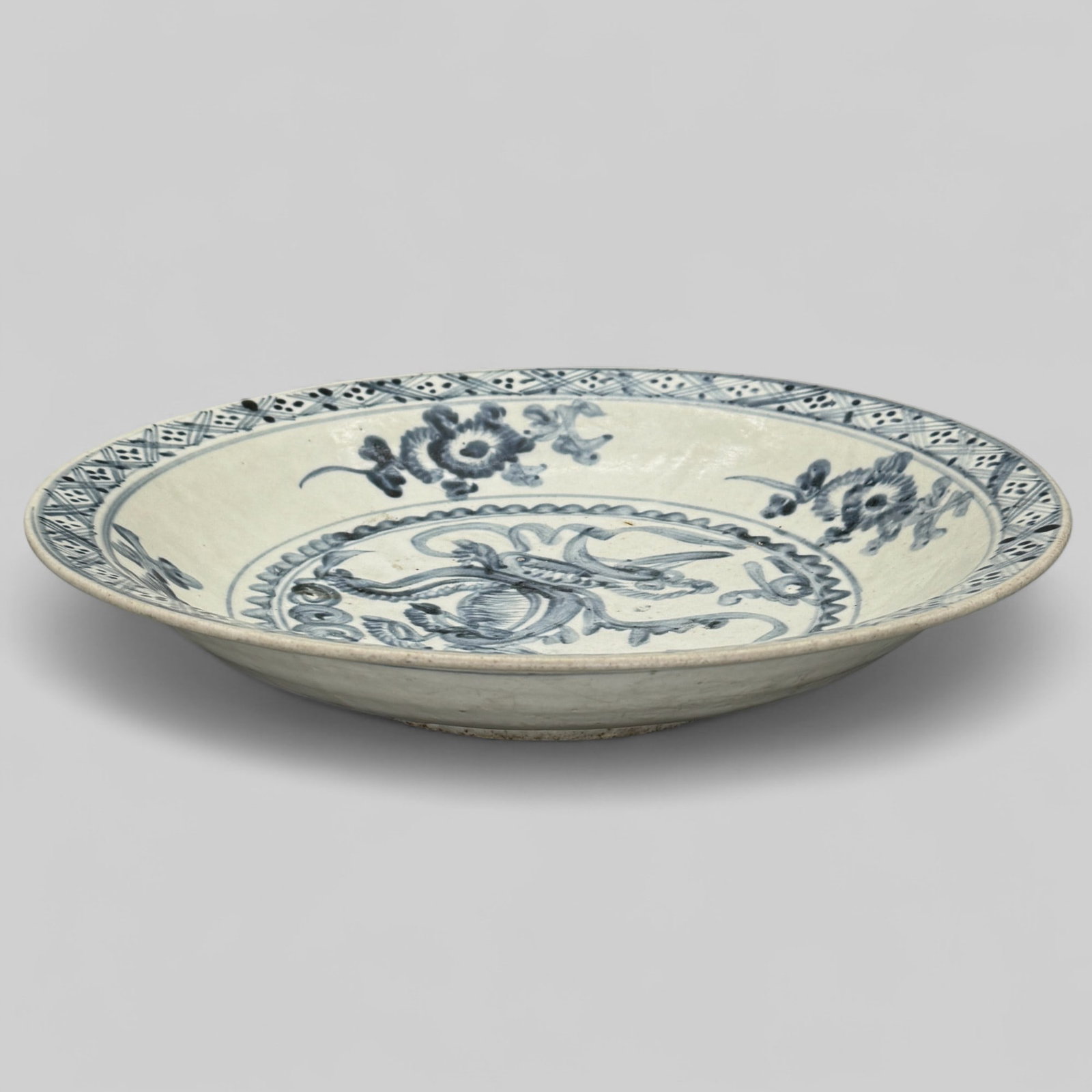 Monumental Ming Blue and White Charger: With interior spotted decoartion around the rim, florals and decoration to the bottom. Ribbed decoration to exterior. Foot is unglazed. Diameter: 14.5" PROVENANCE Private Midwestern Collection, acquir
