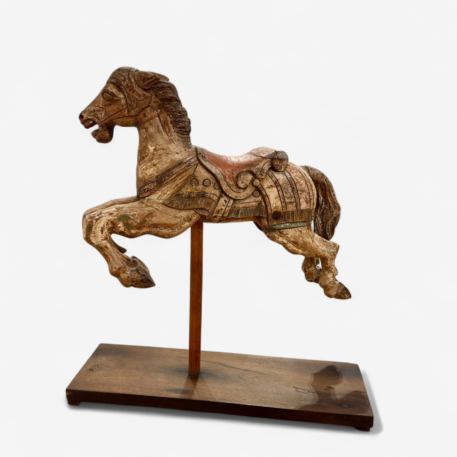 Early 20th Century Carved and Polychromed Carousel Horse: A horse with outstretched legs, evidence of old paint, carved wood in sections, all on stand. Unmarked. Ht. 44", lg. of horse 36.5".