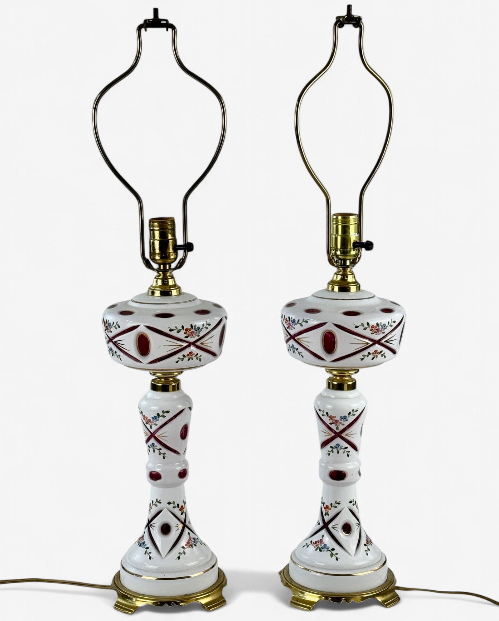 Pair of Milk and Cranberry Glass Lamps: A pair of milk glass lamps with cranberry pockets, floral designs throughout, each with shades. Ht. of each 28".