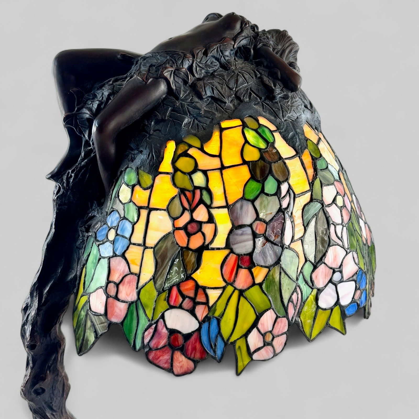 E. Thomasson Art Nouveau Stained Glass Lamp: A bronze and stained glass art nouveau lamp, signed by Emil Thomasson to the base. Nude, reclining female figure to the top and stained glass shade. Height: 29"
