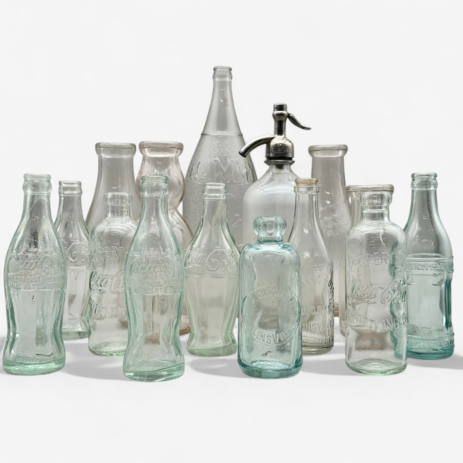 Large Glass Bottle Collection: Including six early Coca Cola bottles, seven Collinsville, Illinois related bottled, one Mammy bottle and one blown glass bottle. Tallest height: 14"
