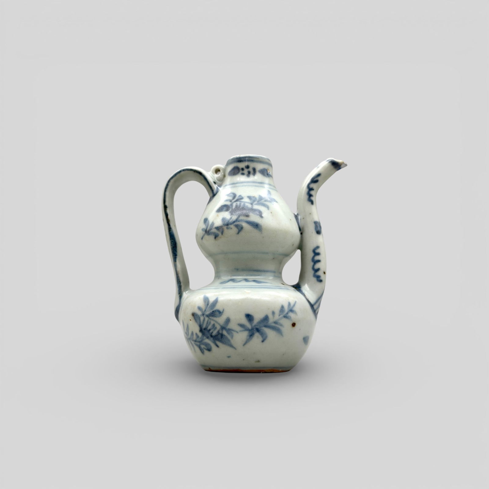 Ming Blue and White Porcelain Ewer: Porcelain with underglaze blue decoration. A small ewer of double-gourd shape, with a loop between the tapering neck and flat handle for fastening a cover. Unglazed base. 4.5" ht.
