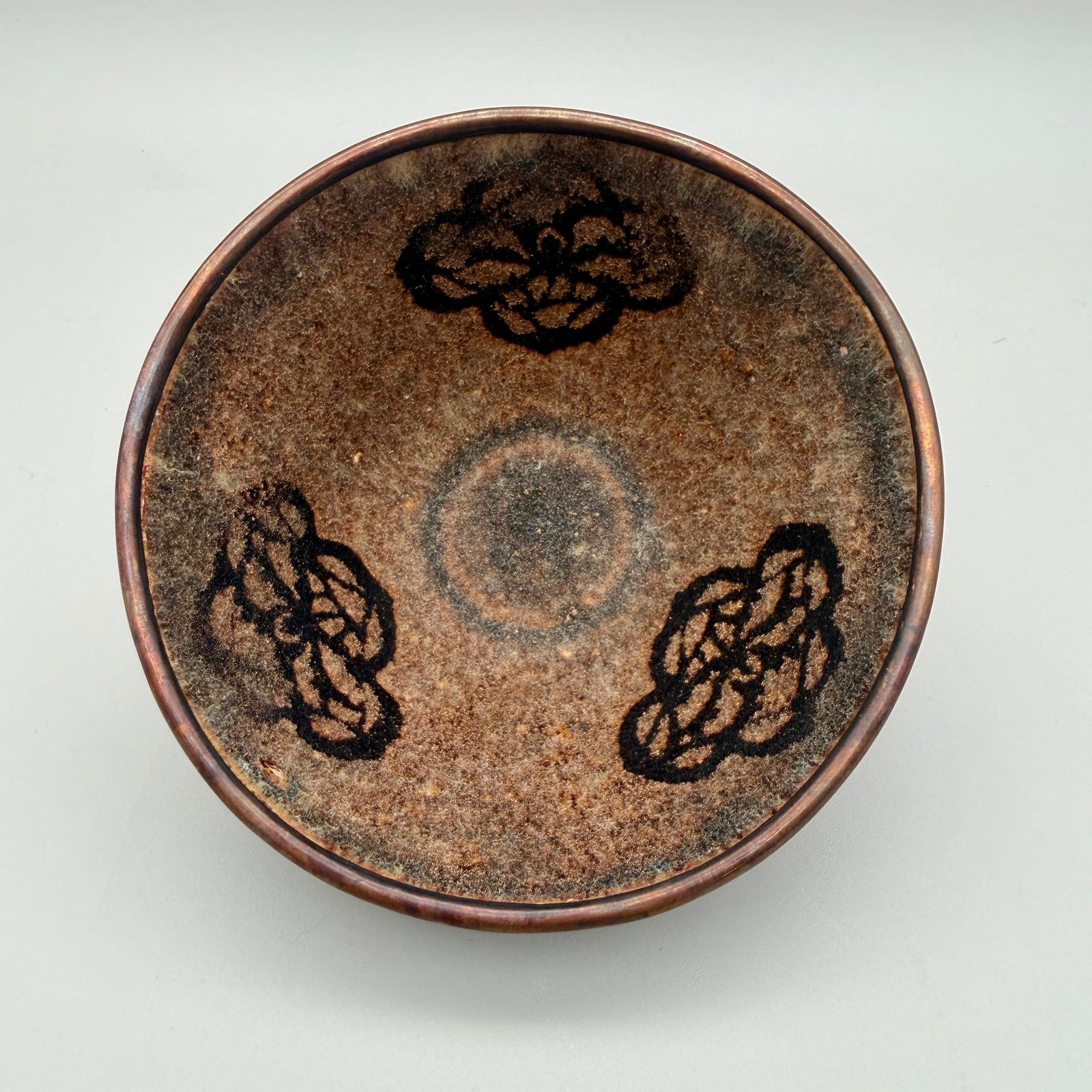 Jizhou Ware Paper-Cut Resist-Decorated Tea Bowl: Song/Yuan Dynasty. The exterior in a tortoise shell glaze, the interior with paper-cut resist-decorated blossoms and speckled glaze, the rim with later Japanese gilt. Ht. 2.25", 4.25" diameter.