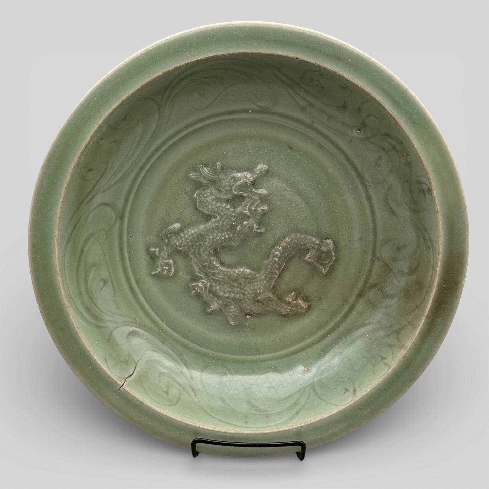 A Large Longquan Celadon "Dragon" Dish: Yuan dynasty. with rounded sides rising to a flat everted rim, the interior centred with a coiling dragon with its mouth held agape. The interior also decorated with a lappet of chrysanthemum petals,